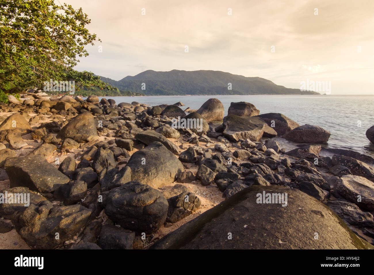 Die großen Felsen von ABC Beach auf Tioman Island bei Sonnenuntergang mit Blick auf Ferne Landzunge am Horizont. Tioman Island, Malaysia. Stockfoto