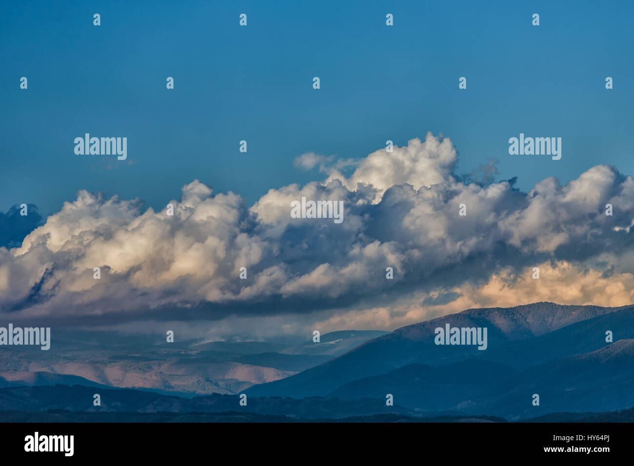 Cumulus-Wolken über schneebedeckte Berge bewegen Stockfoto