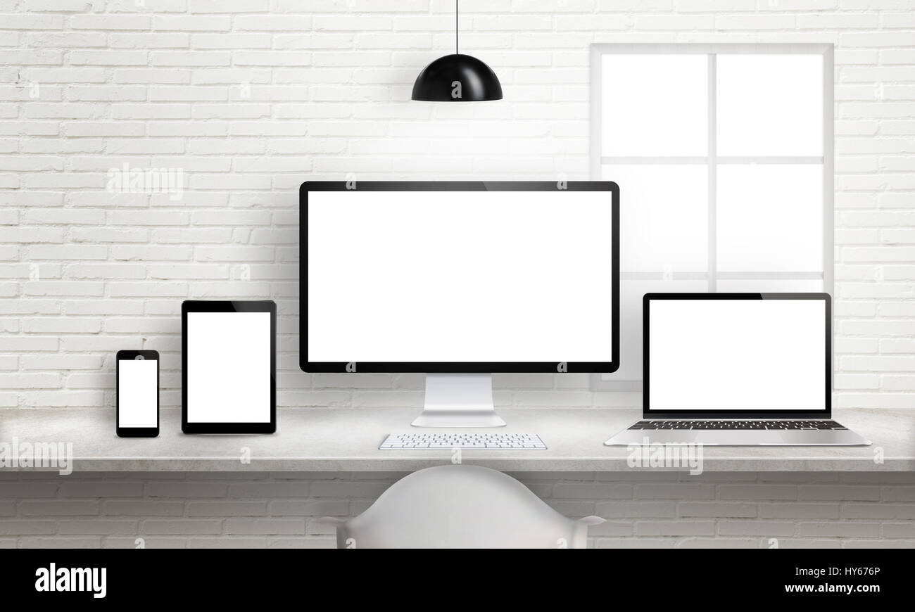Mehrere Geräte am Schreibtisch für ansprechende Website-Design-Präsentation. Weiße Mauer im Hintergrund. Stockfoto
