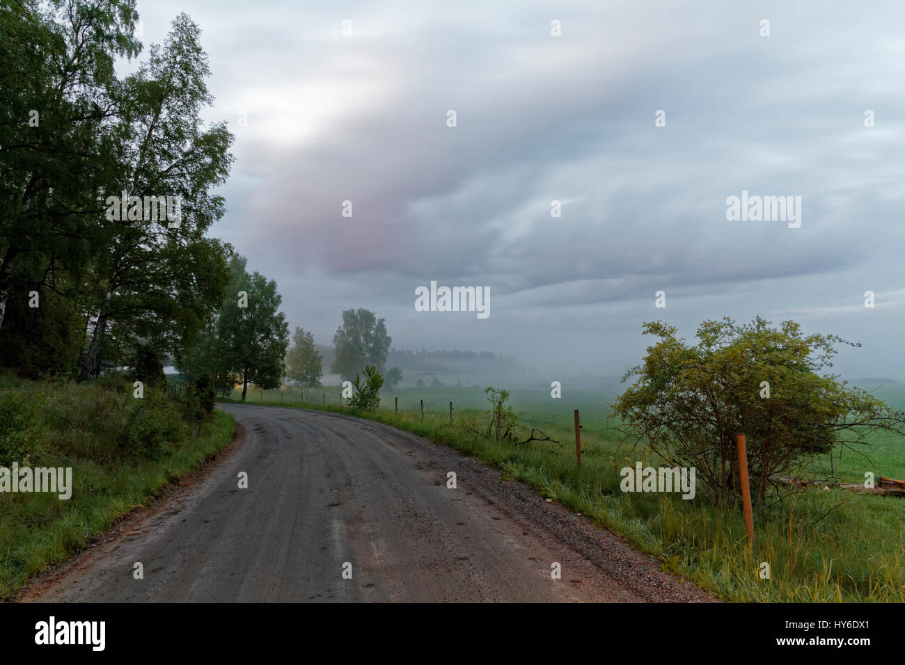 Trüb bewölkt am Abend und einer kurvigen Schotterpiste Stockfoto