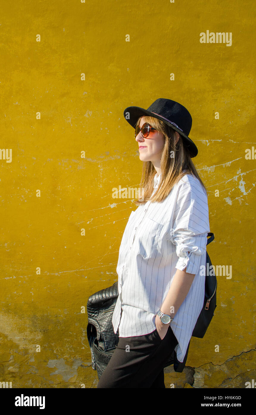 Modebewusste junge Frau gegen Vintage gelbe Wand Stockfoto