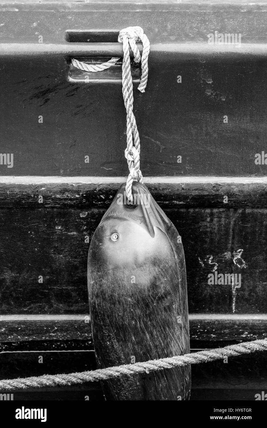Schwarz-weiß-Bild aus einem Kunststoff Kotflügel durch ein Seil an der Seite eines 15-04 auf der Regent's Canal, King's Cross, London, UK günstig hängen Stockfoto