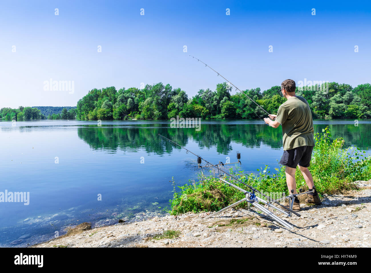 Karpfen Sie Abenteuer Angeln, Angeln. Angler ist das Angeln mit Carpfishing Technik im Süßwasser, in einem schönen Sommertag mit hellblauen Himmel Stockfoto