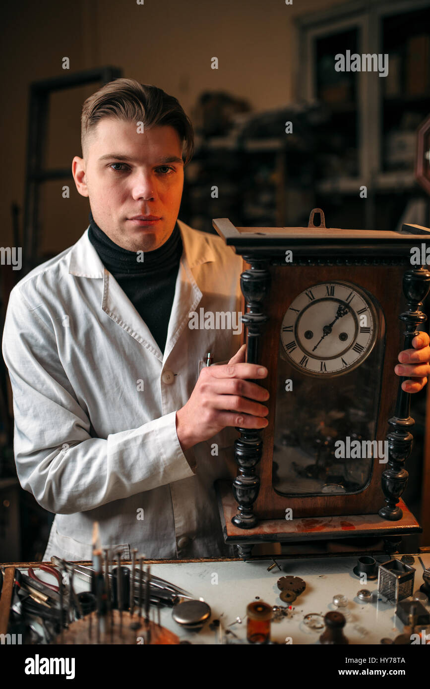 Uhrmacher stellt den Mechanismus der alte Wanduhr in der Werkstatt