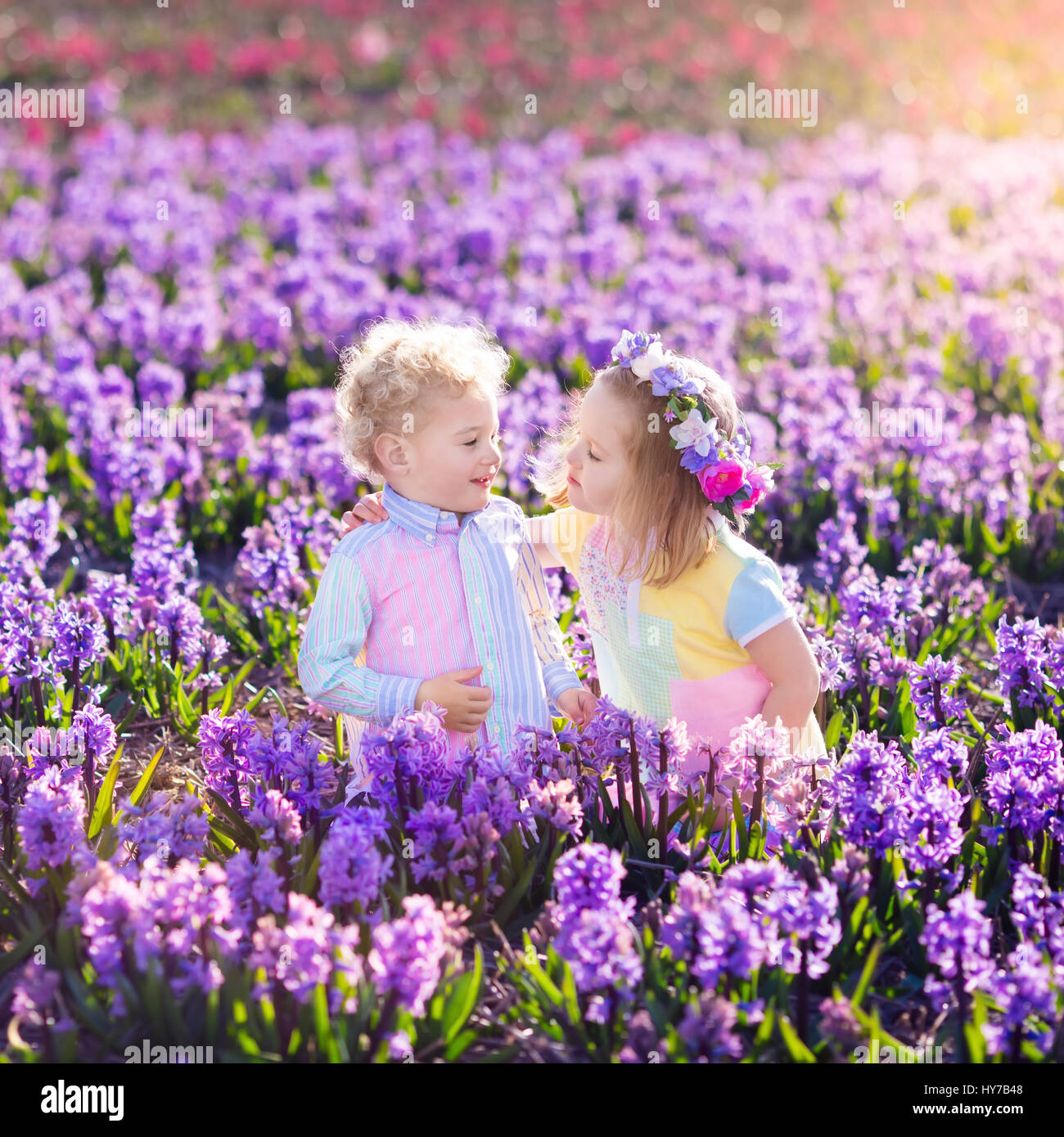 Kinder im Garten. Kinder spielen im Freien auf Hyazinthen Wiese. Kleine Mädchen und jungen, Bruder und Schwester, arbeiten im Garten, Hyazinthe Blumen Pflanzen, wa Stockfoto