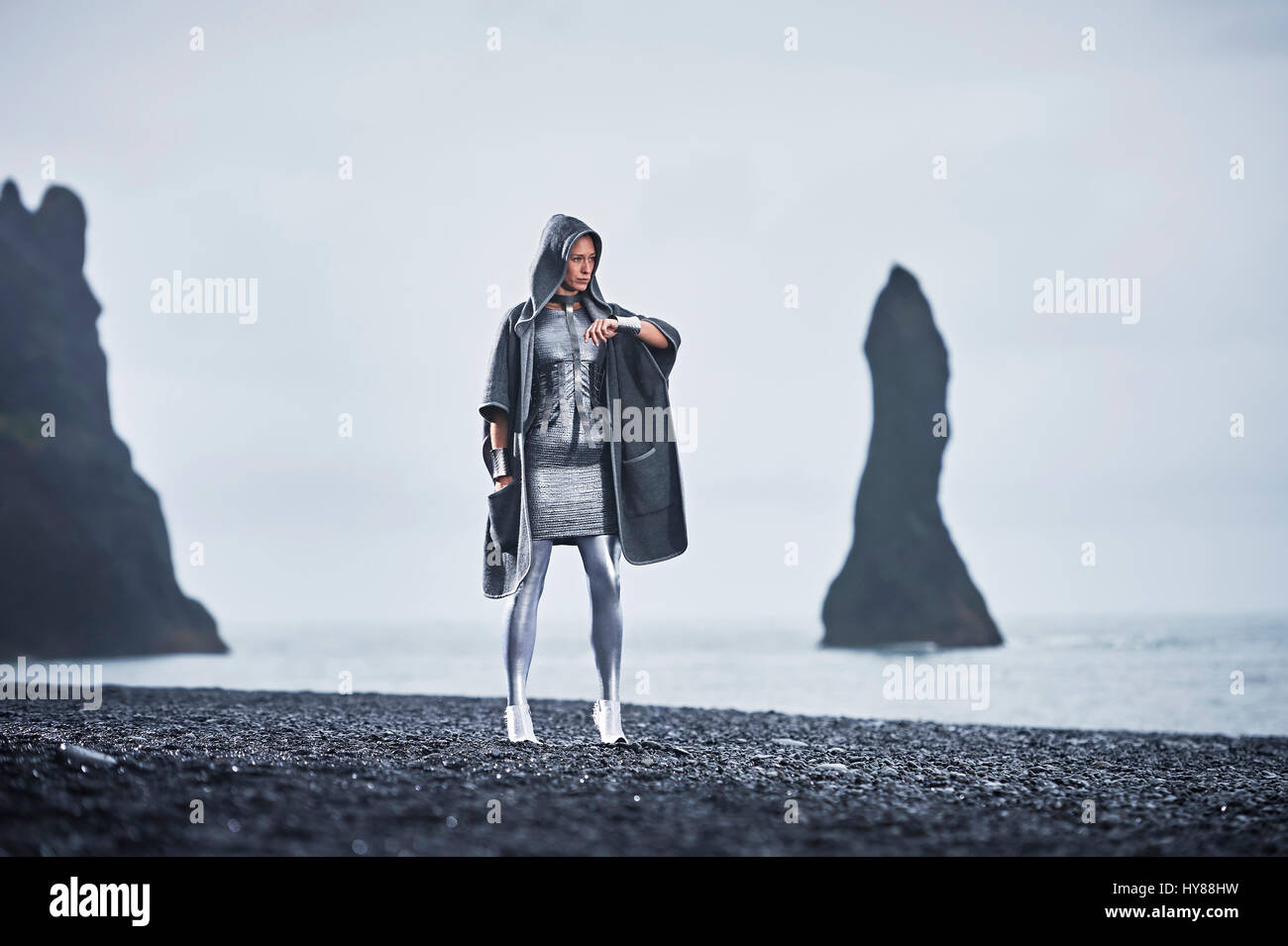 Getarnte junge Frauen im silbernen Outfit stehen mit Zuversicht vor Basaltfelsen im Süden Islands Stockfoto