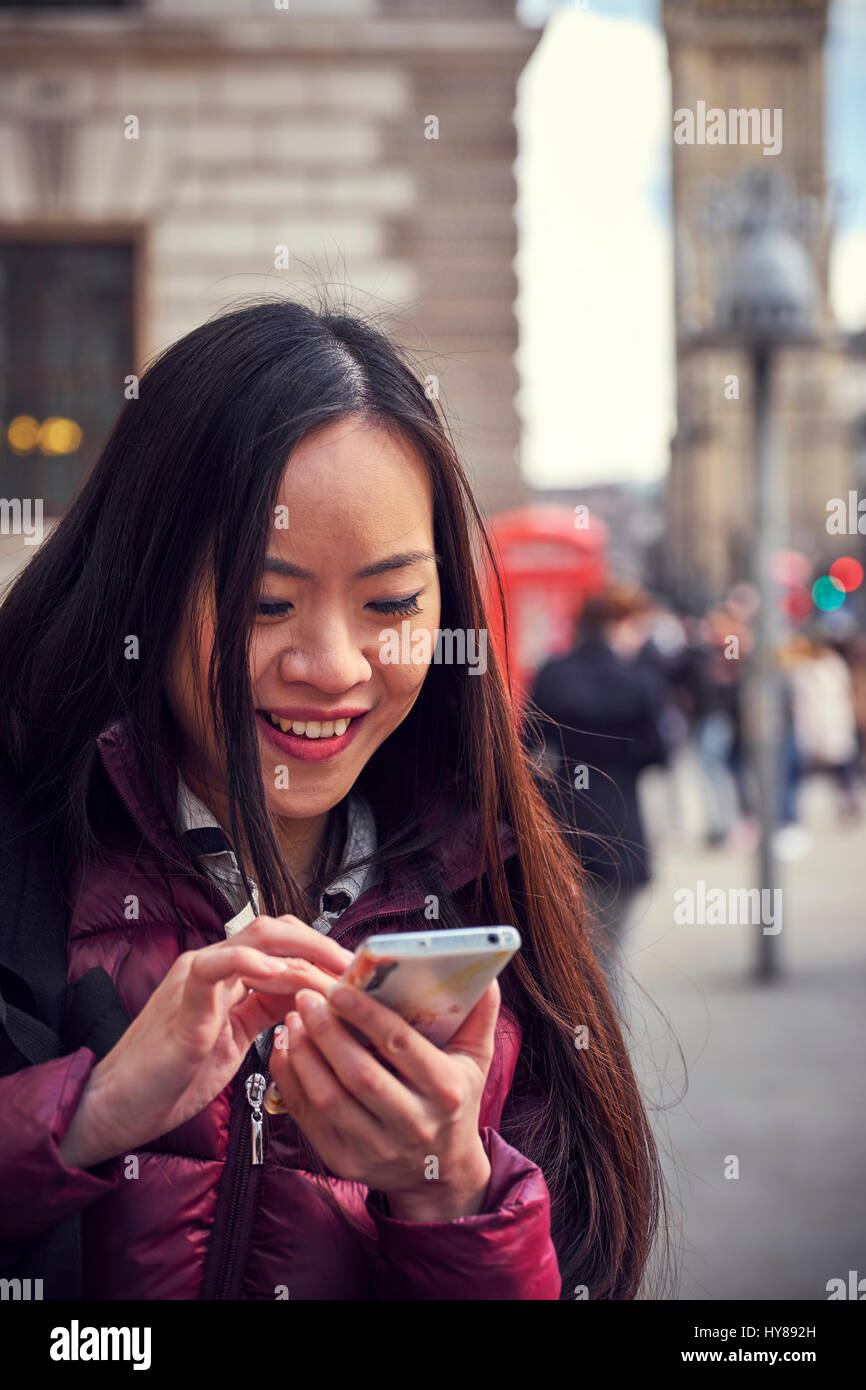 Eine junge Japanerin mit ihrem Smartphone in London Stockfoto
