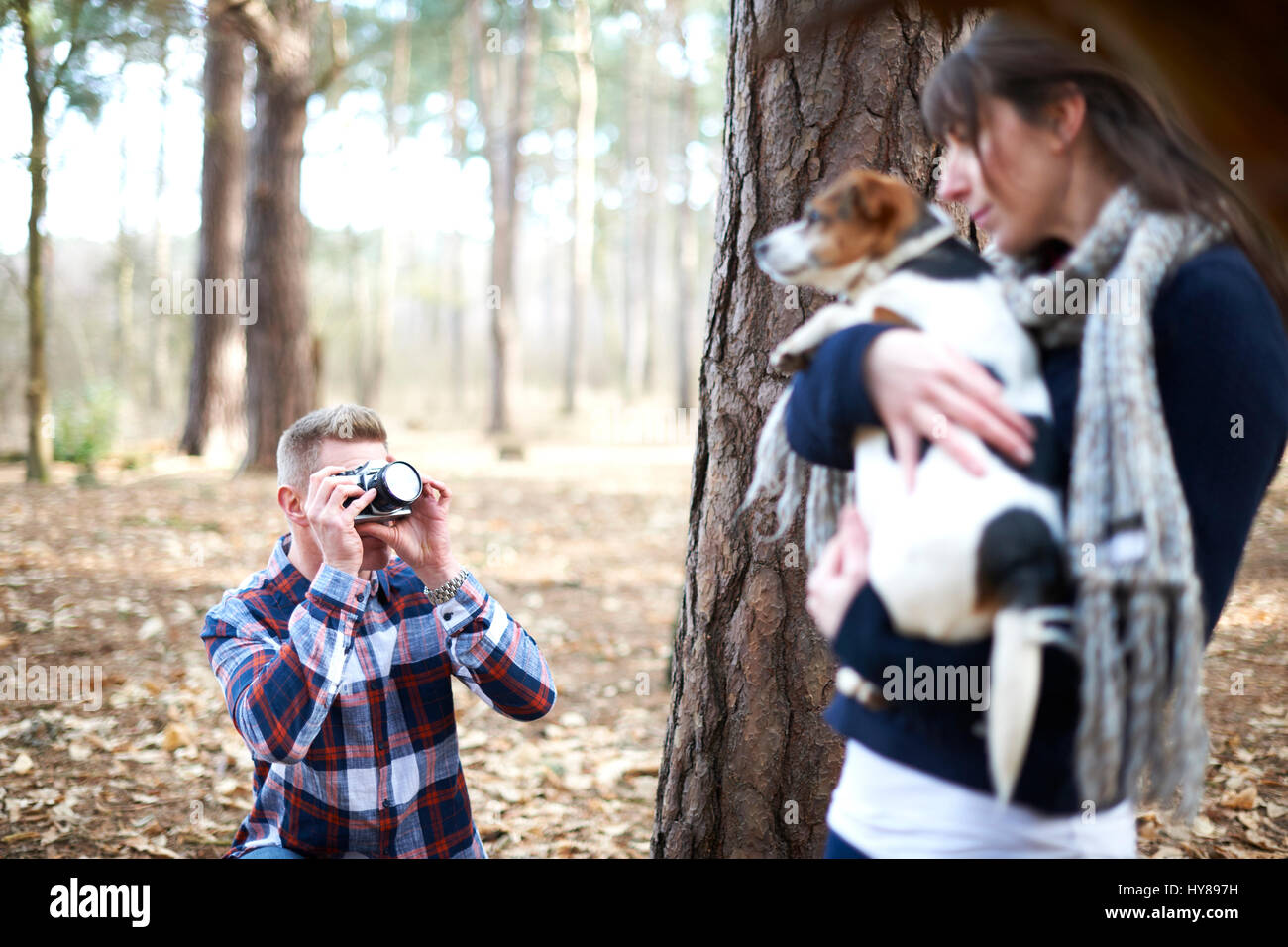 Ein Mann nimmt ein Foto von seiner Gefährtin und ihr Hund, wie sie in den Wald gehen Stockfoto