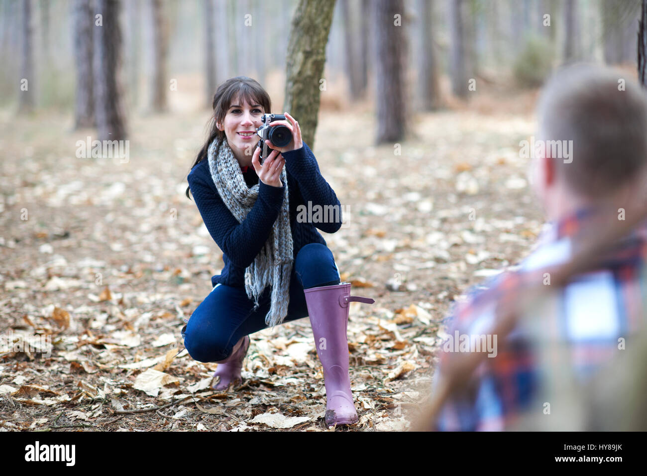 Eine junge Frau nimmt ein Foto von ihrem Partner im Wald Stockfoto