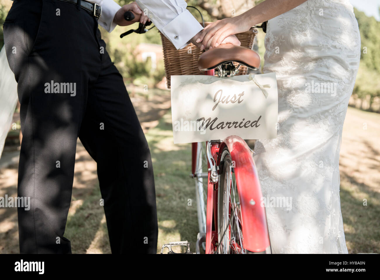 Eine Braut und Bräutigam schieben Sie ein Fahrrad mit einem Schild Just Married auf der Rückseite Stockfoto