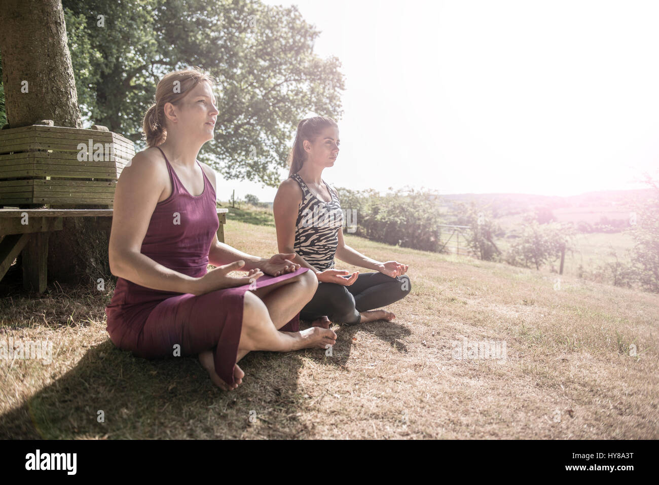 Zwei Freundinnen sitzen und sich mit Yoga außerhalb Stockfoto
