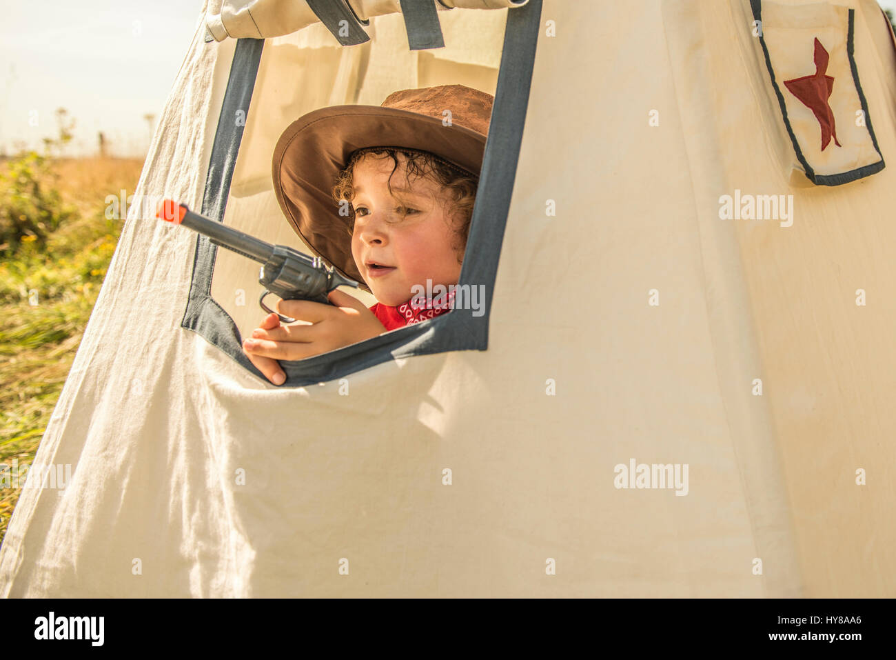 Ein kleiner Junge spielt Cowboys und Indianer draußen in der Sonne Stockfoto