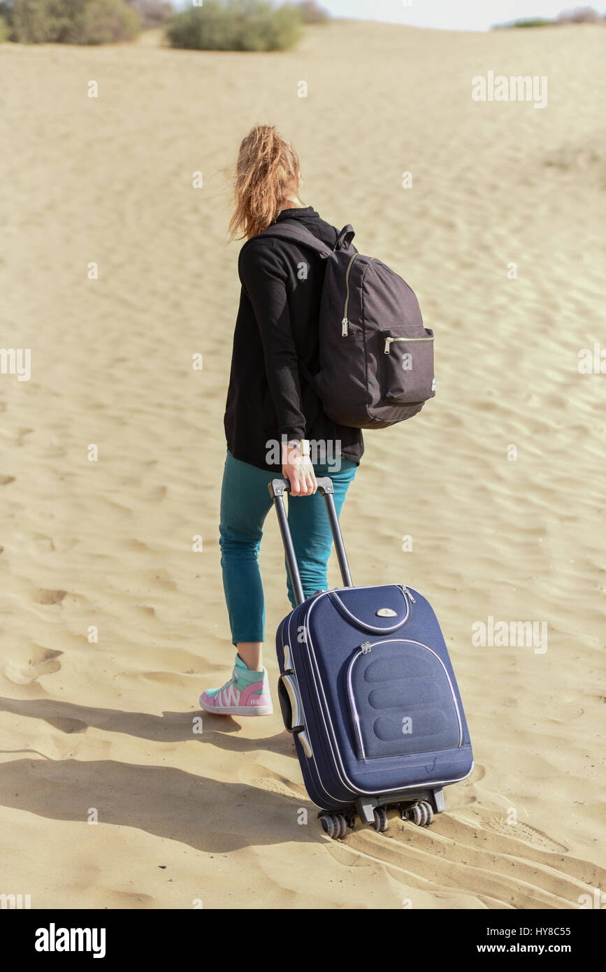 Mädchen zieht Gepäck auf einem sand Stockfoto