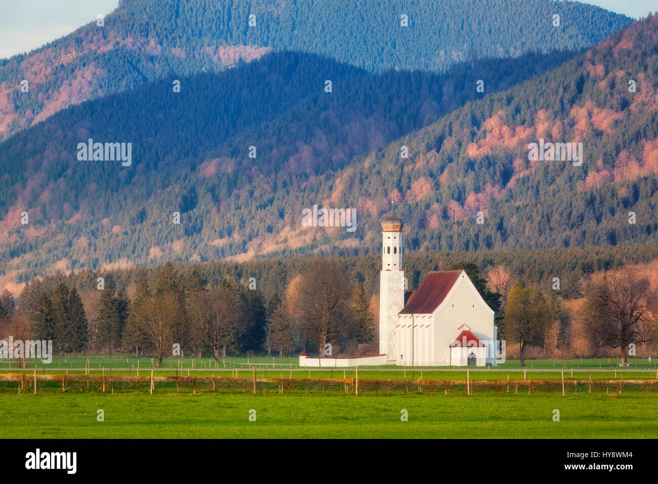 Schöne weiße Kirche auf der grünen Wiese vor dem Hintergrund der Bäume und Berge in Deutschland. Frühling Landschaft in Europa. Kapelle und grünen Hügeln Witz Stockfoto