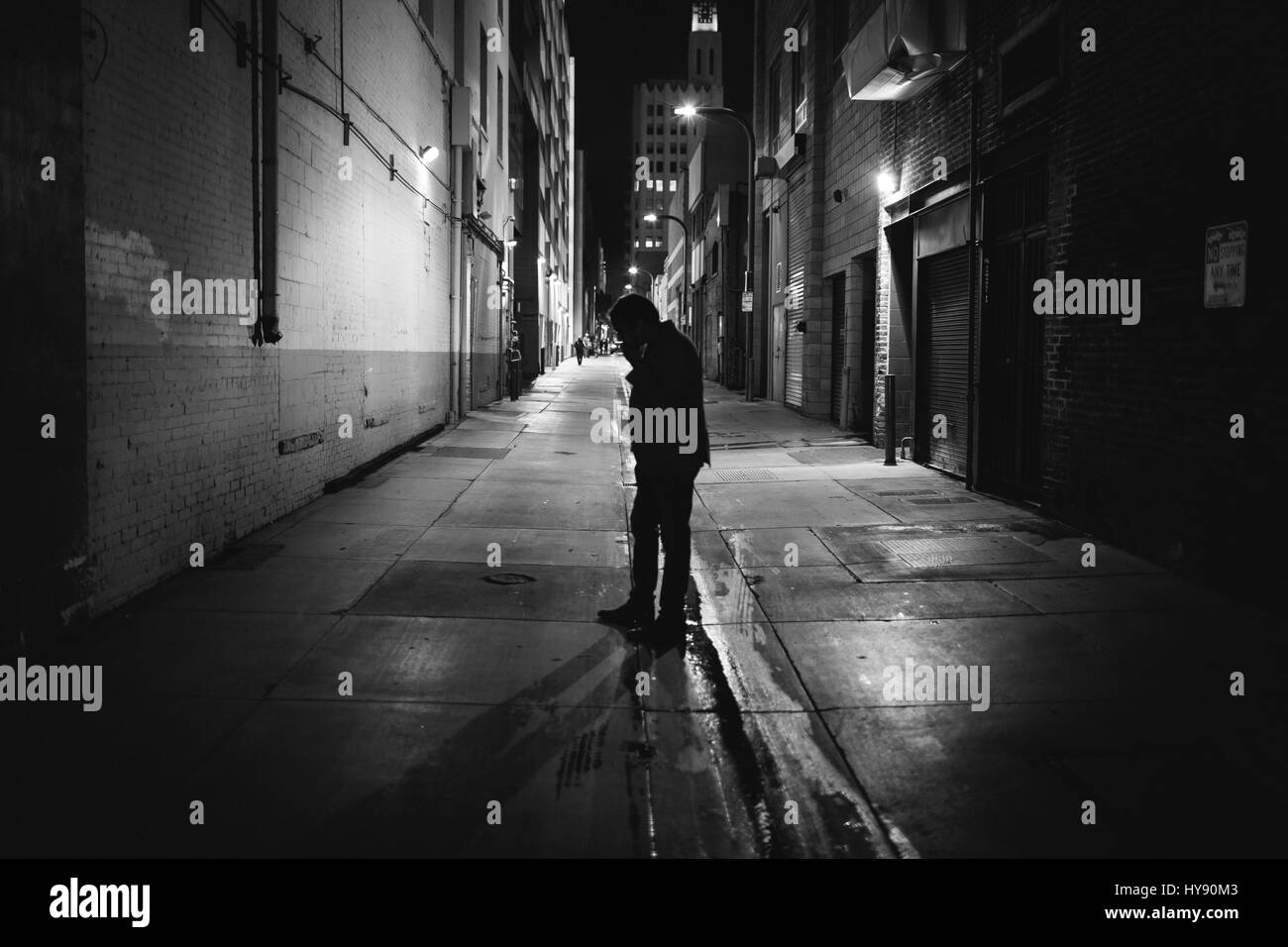 Ein Mann stehend in einer Gasse abseits einer Straße in Santa Monica. Er scheint zu eine Zigarettenpause vom einer Party statt, die in einem Restaurant nächsten Doo geschieht. Stockfoto
