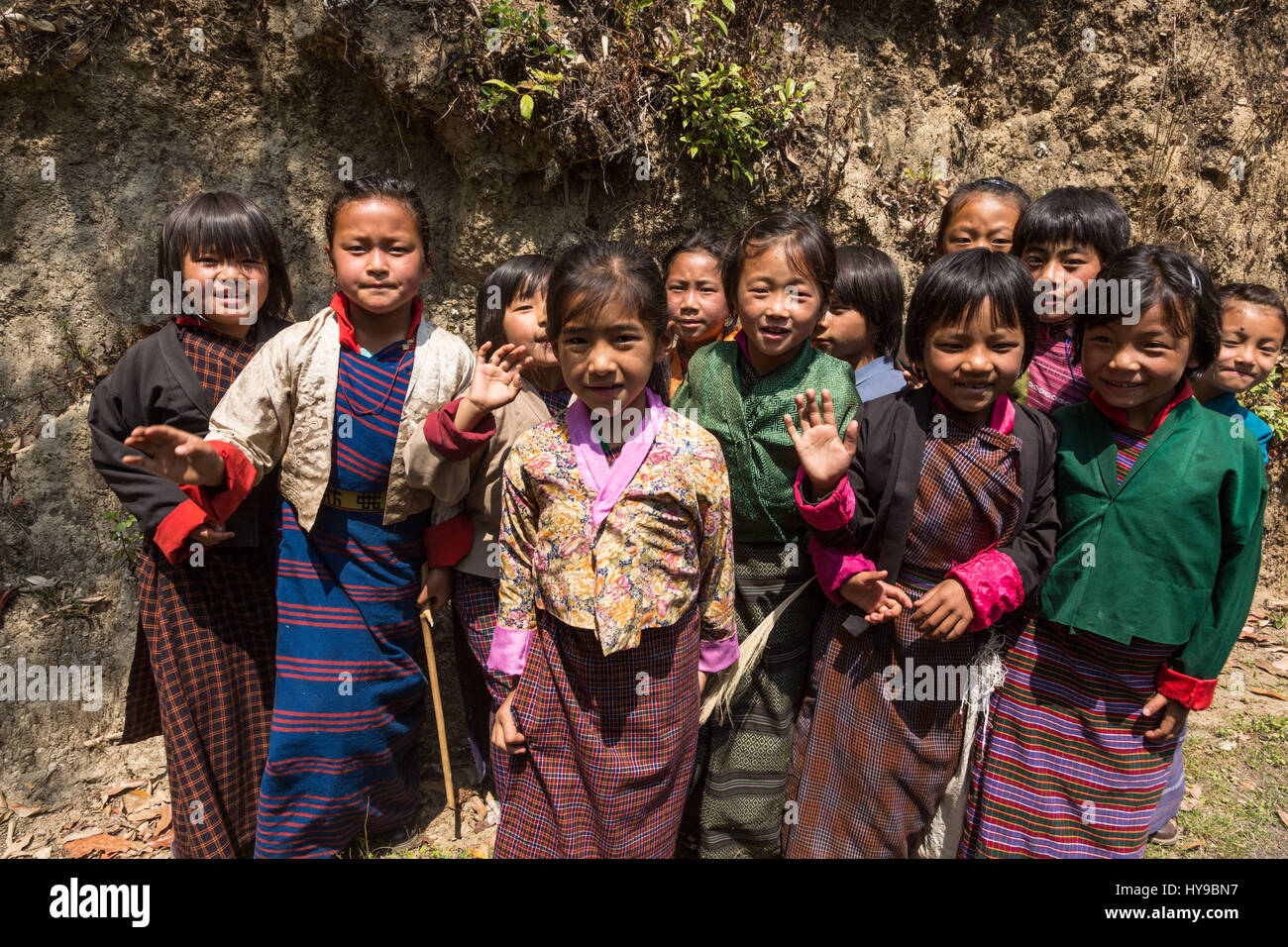 Junge Schulmädchen in traditionellen Kira Röcken und Jacken Tego posieren für ihr Bild von der Straße in Talo, Bhutan. Stockfoto