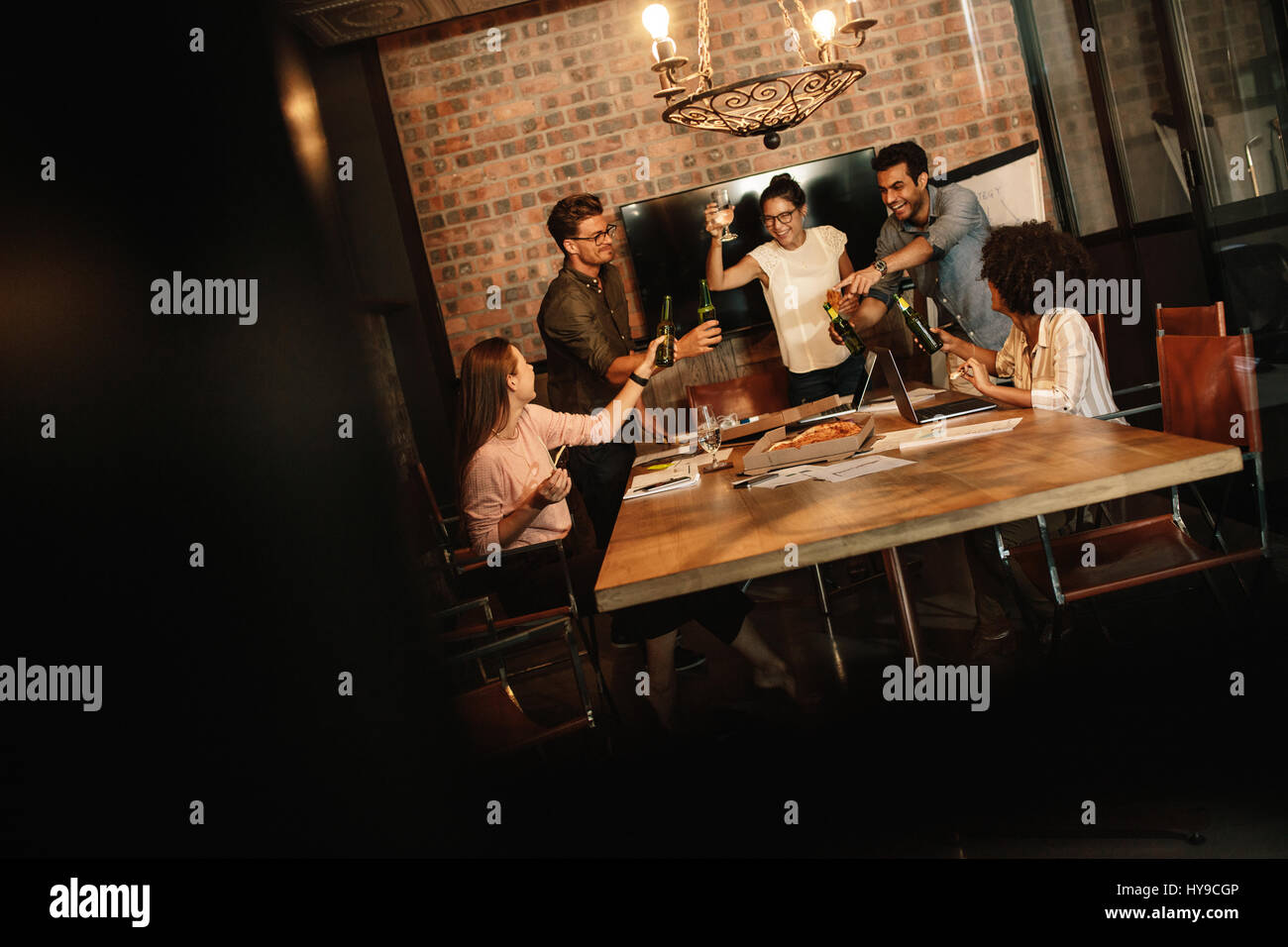 Gruppe von erfolgreichen Jungunternehmen Profis feiern im Büro Konferenzraum. Verschiedene Business-Team mit Speisen und Getränken an Start-up-Office Stockfoto