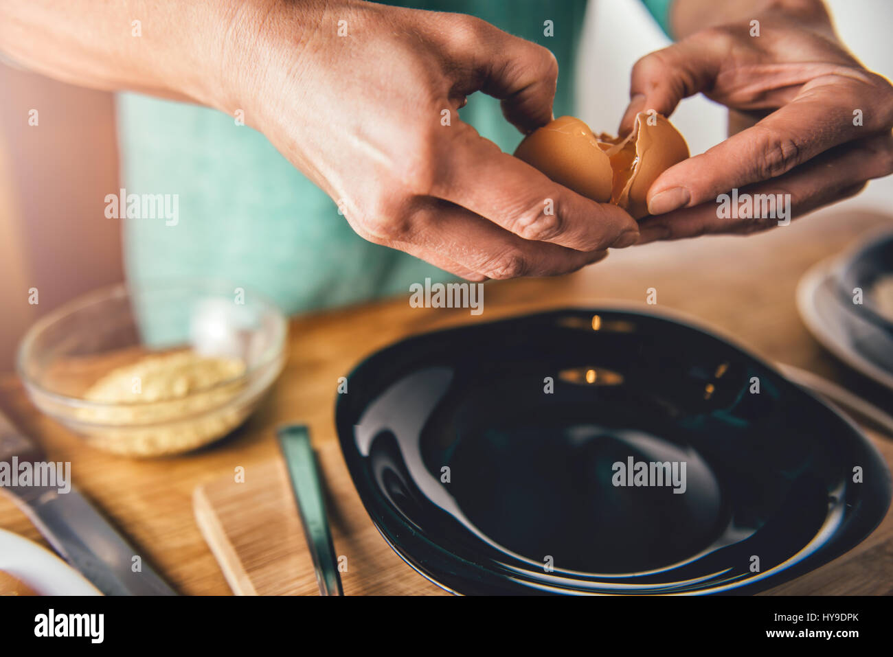 Frau, Kochen und Eiern in die Platte in der Küche zu Hause zu brechen Stockfoto
