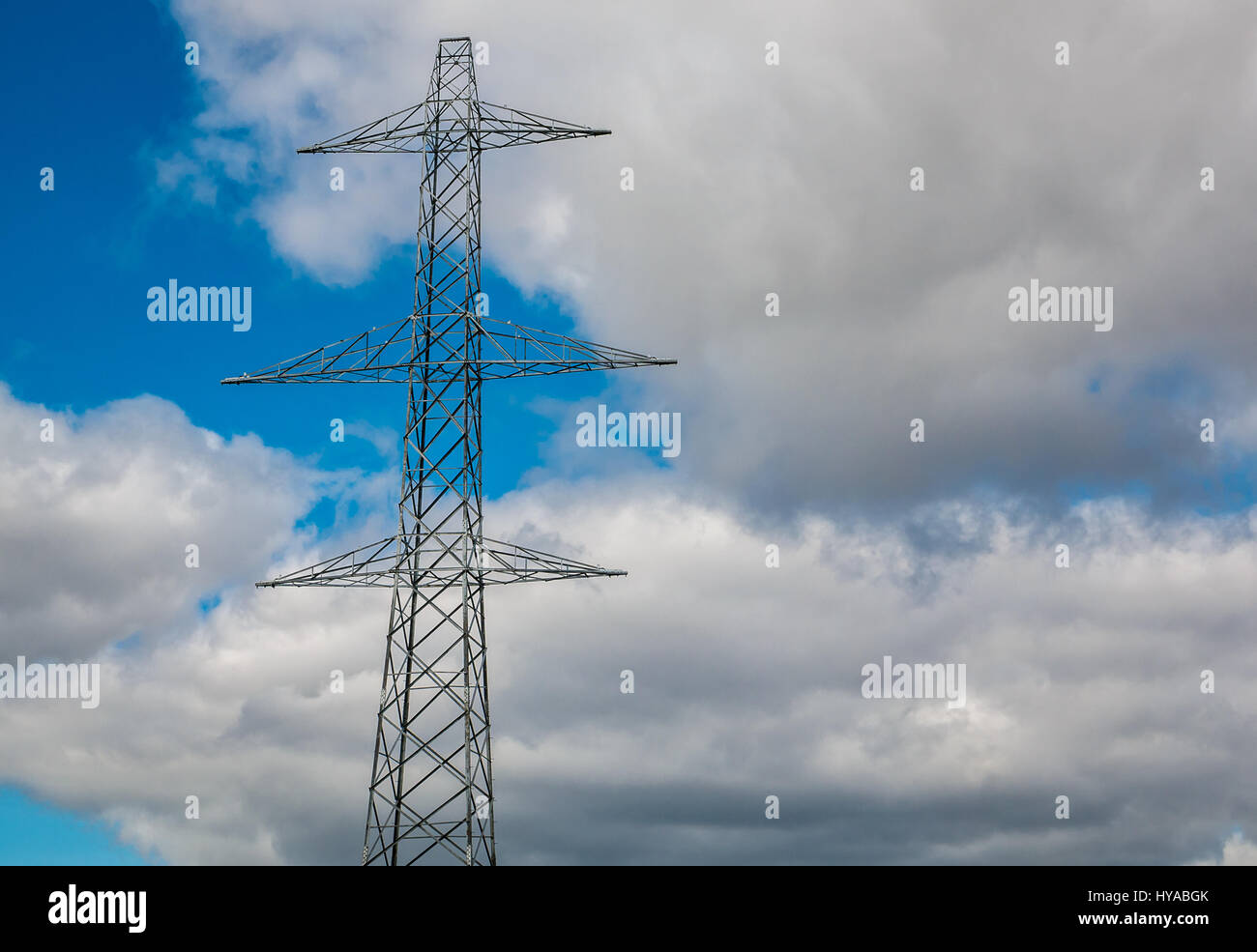 Blick auf den hohen Strompylon-Turm mit Kabeln über dem Kopf gegen einen blauen Himmel mit weißen flauschigen Wolken, Schottland, Großbritannien Stockfoto
