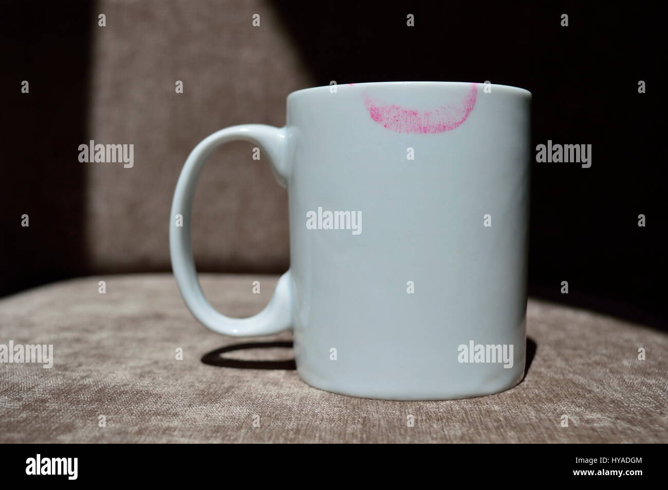 Weiße Tasse mit einem Lippenstift print isoliert auf braunem Hintergrund geteilt durch Licht und Schatten Stockfoto