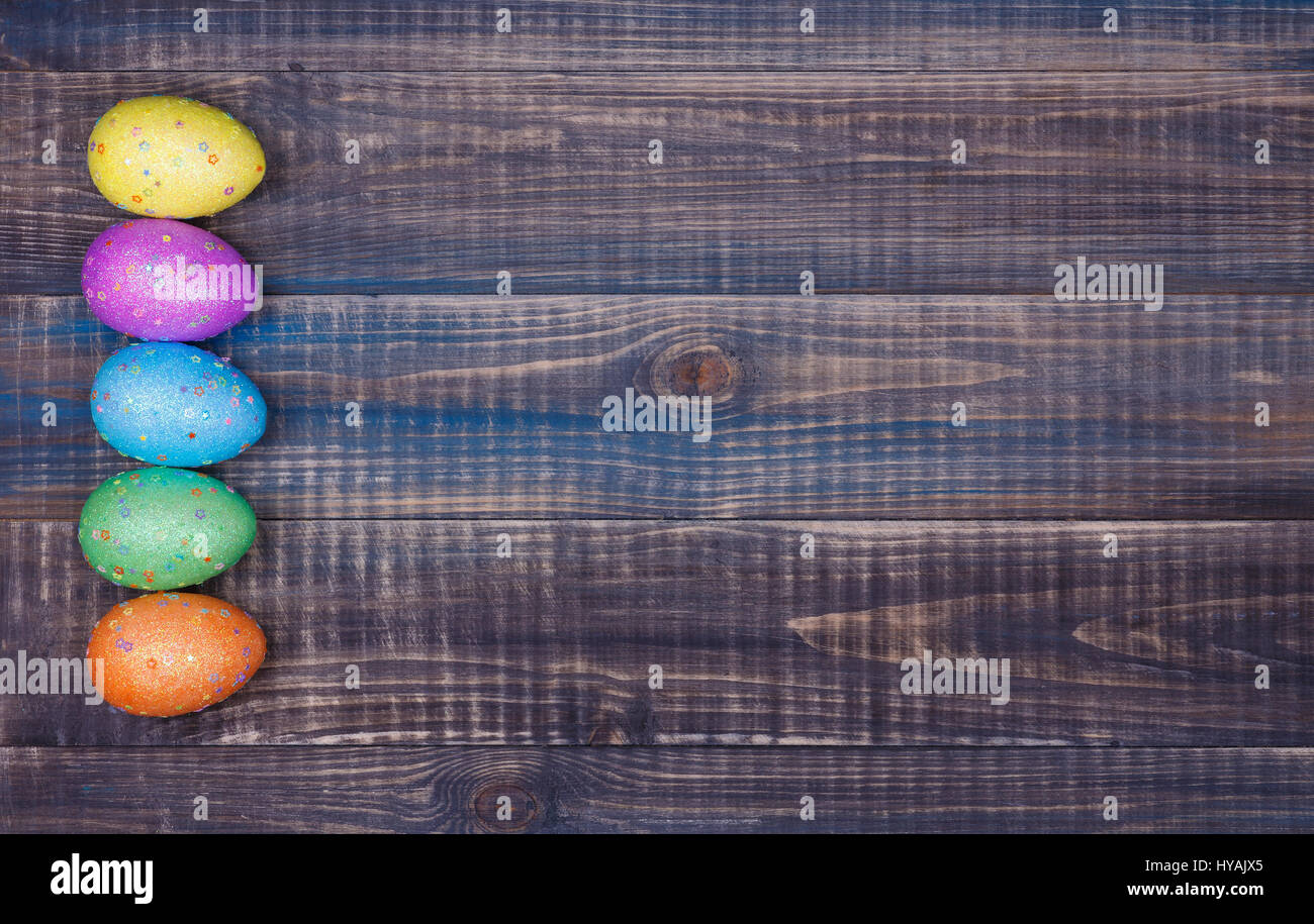 Auf einem Holztisch liegen fünf bunte Ostereier. Platz für text Stockfoto