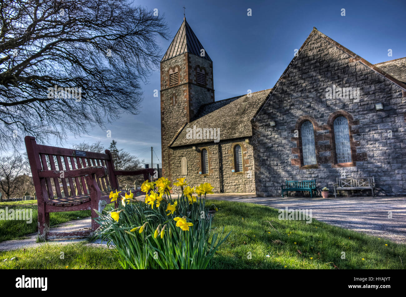 Colvend Kirche mit Narzissen und Bank High Dynamic Range Image. Stockfoto