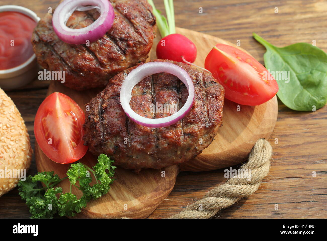 Rindfleisch-Burger mit Zwiebeln und Sauce auf Schneidebrett Stockfoto