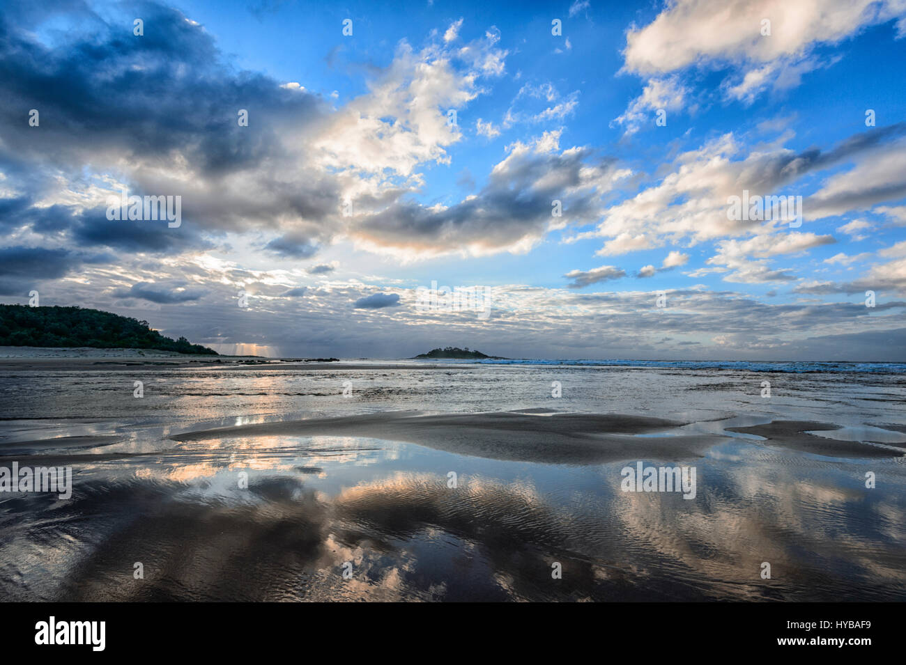 Stimmungsvollen Blick auf Wolken Reflexionen im Meer bei Sonnenaufgang über Conjola Strand, Shoalhaven, South Coast, New-South.Wales, NSW, Australien Stockfoto