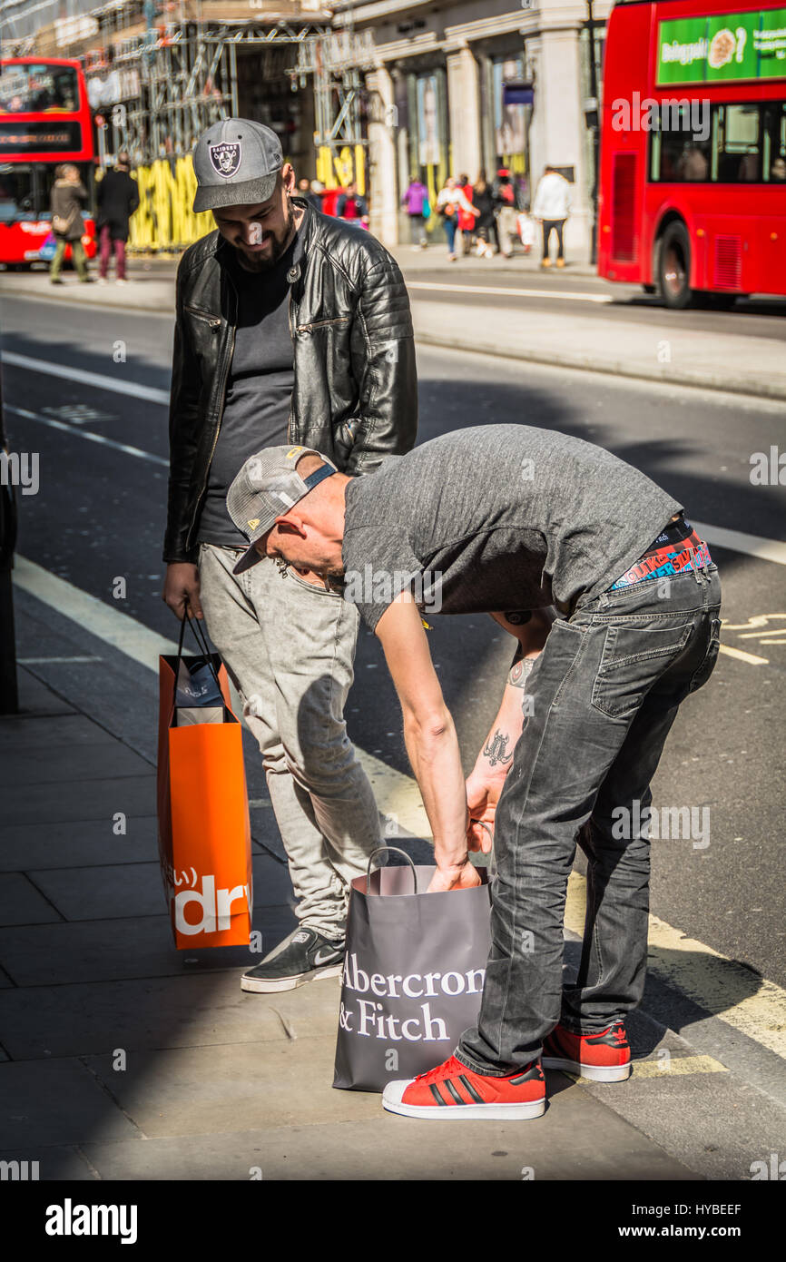 Ein Mann blickt durch seine Abercrombie and Fitch Einkaufstasche auf Regent Street, London, UK Stockfoto