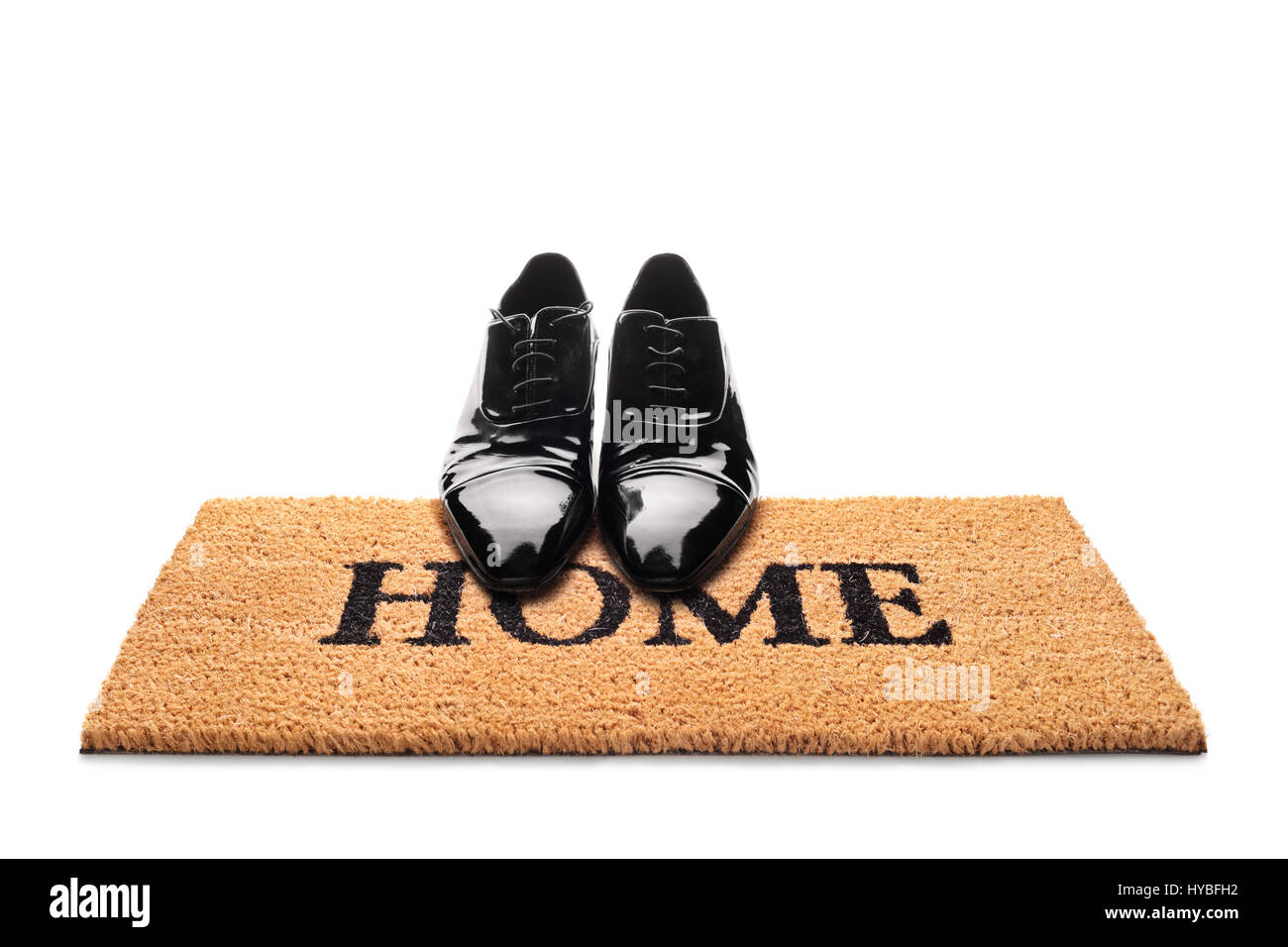 Paar Schuhe auf eine Fußmatte mit dem Wort Heimat geschrieben steht isoliert auf weißem Hintergrund Stockfoto