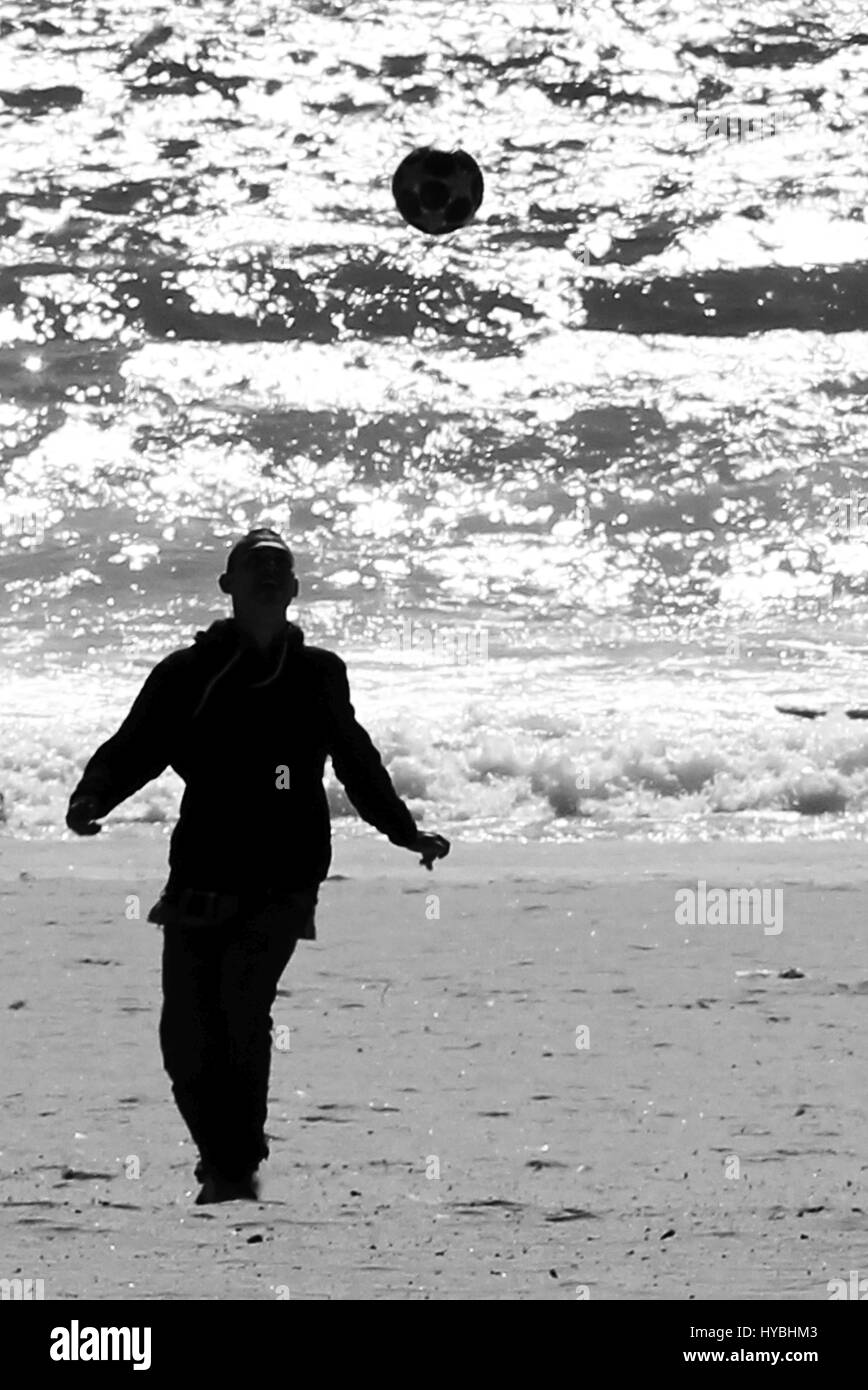 Ein Kind Fußball spielen am Strand mit dem Meer im Rücken Matosinhos. Stockfoto