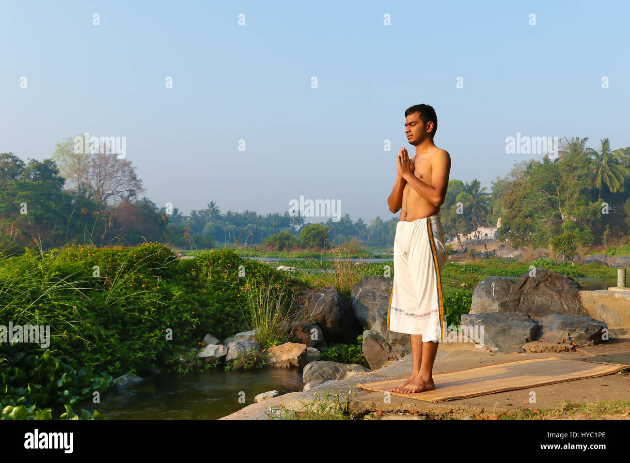 Indischer Mann neben einem Fluss in Süd-Indien Yoga zu praktizieren. Stockfoto