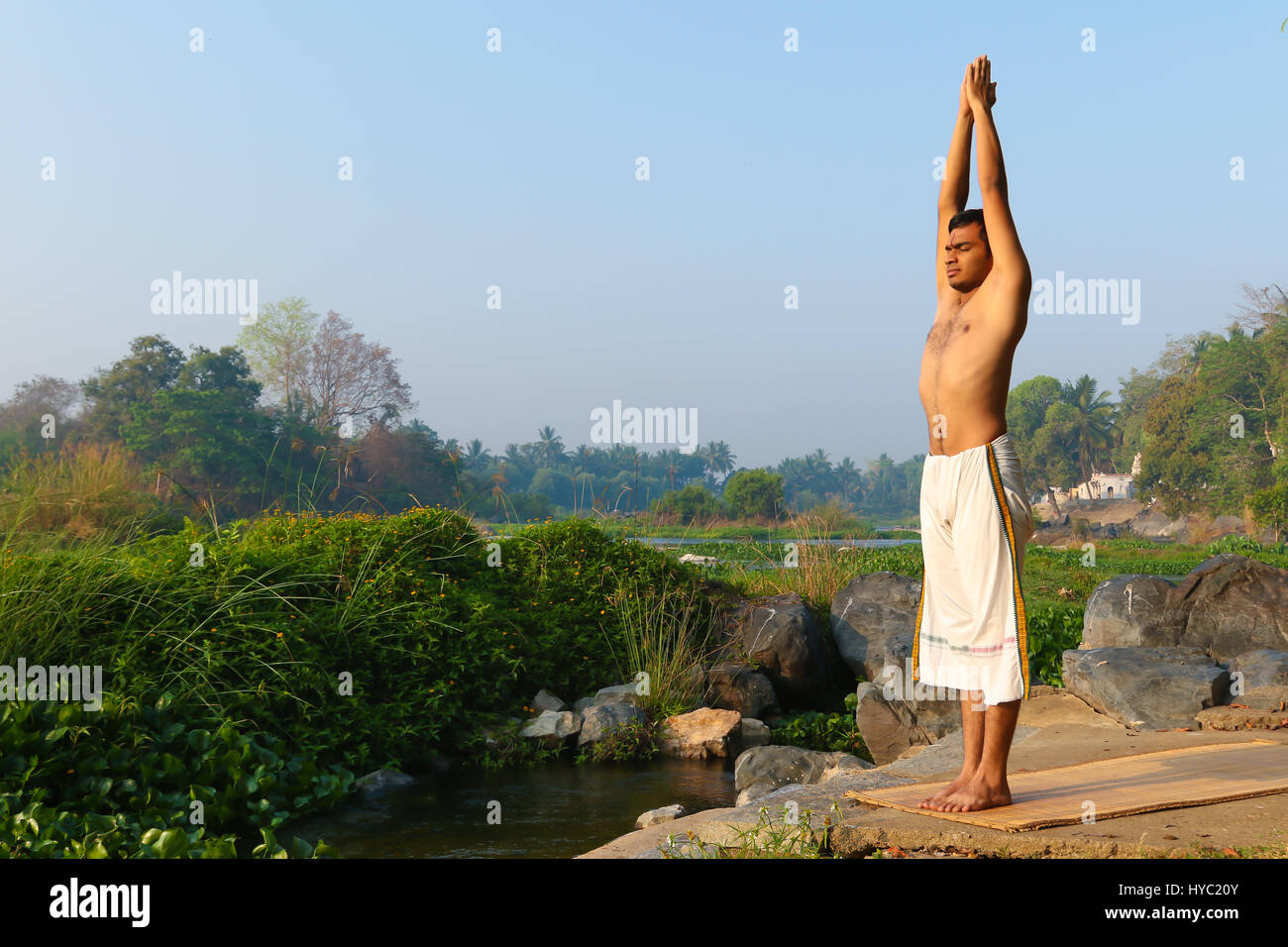 Indischer Mann neben einem Fluss in Süd-Indien Yoga zu praktizieren. Stockfoto