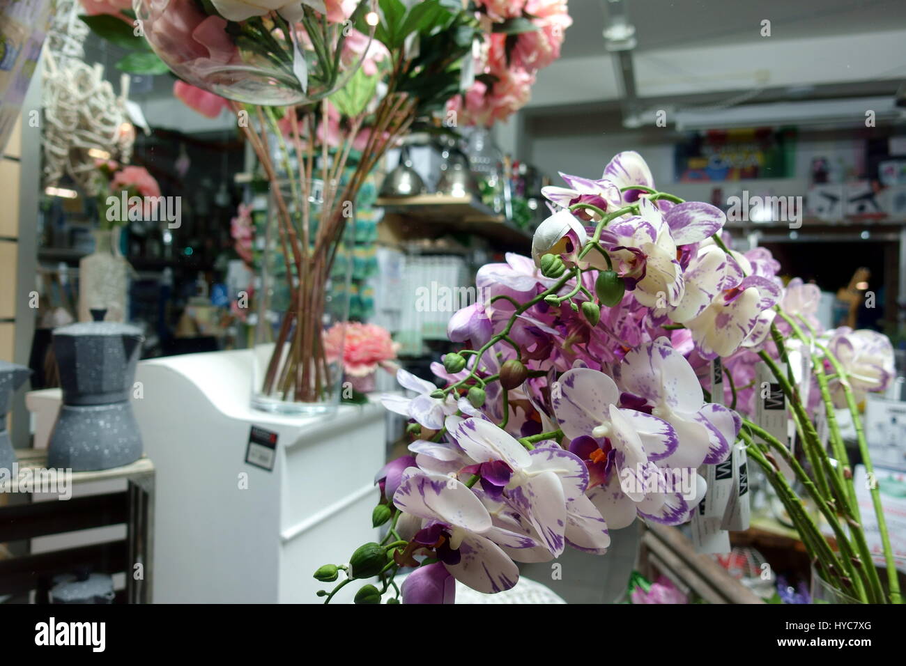 Seidenblumen (lila und weißen Orchideen im Fokus) in einem Schaufenster in  der Nacht - shop künstliche Blumen Serie Stockfotografie - Alamy
