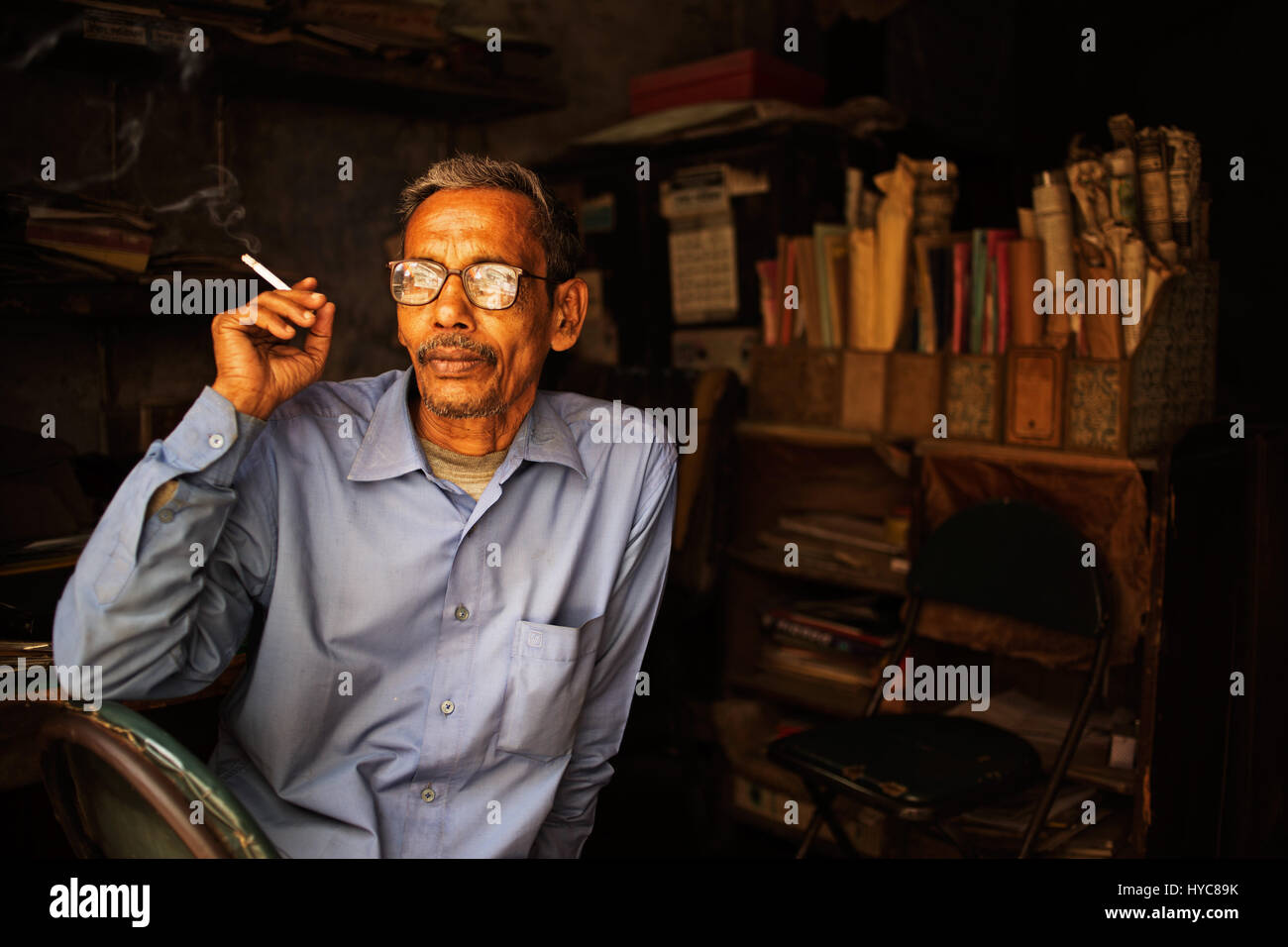 Mann Rauchen in seinem Shop, Dhaka, Bangladesch Stockfoto