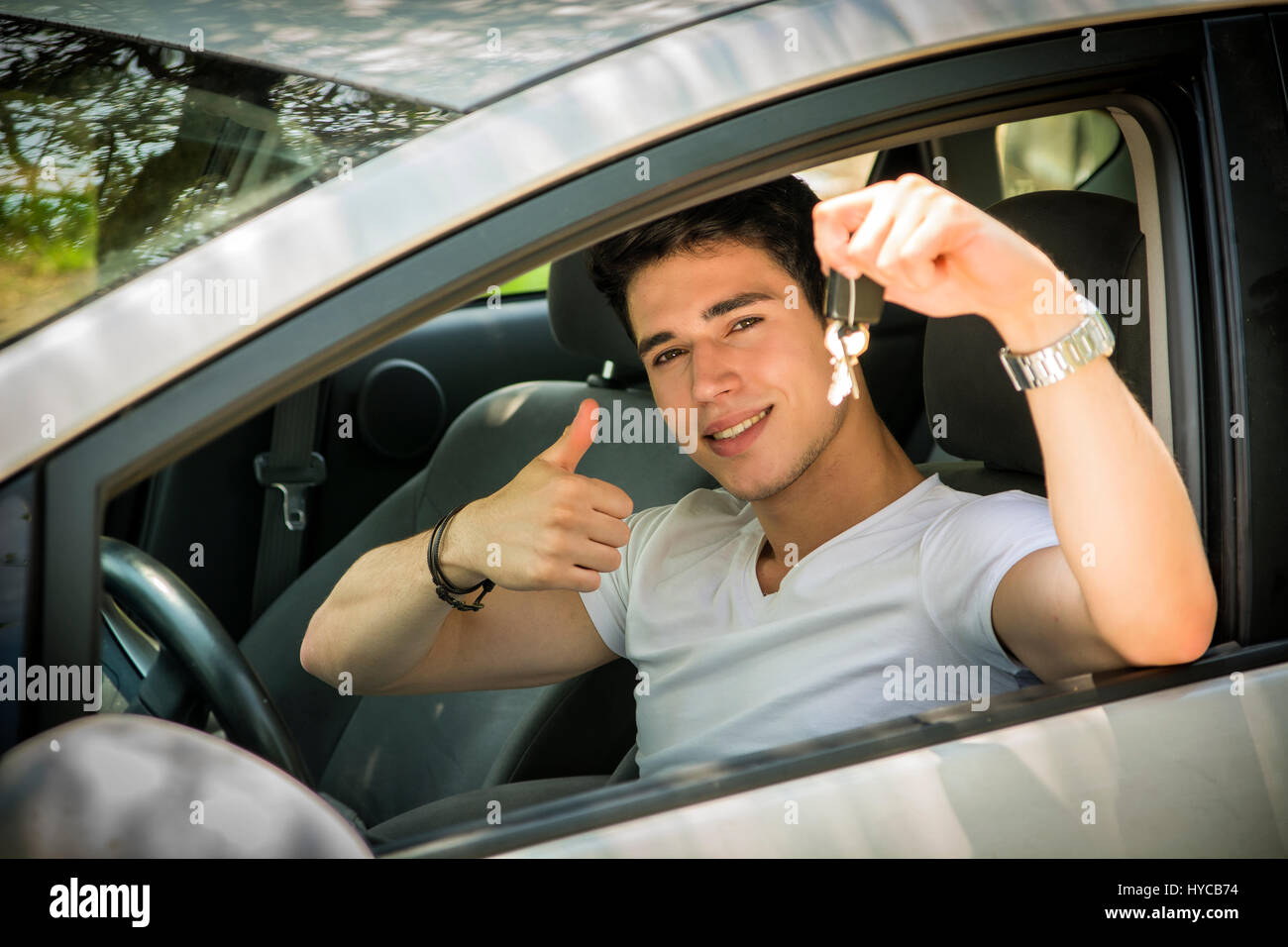 Junger Kerl, der Schlüssel im Auto zeigt Stockfoto