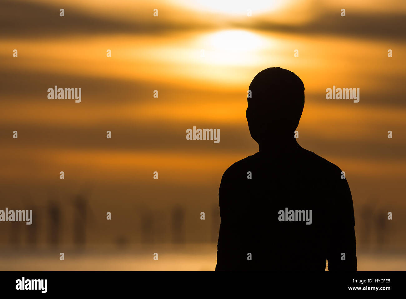 Eines der hundert Ironmen Statuen die Crosby Strand nahe Liverpool, bei Ebbe erfasst, wie die Sonne beginnt zu stellen zu besetzen. Stockfoto