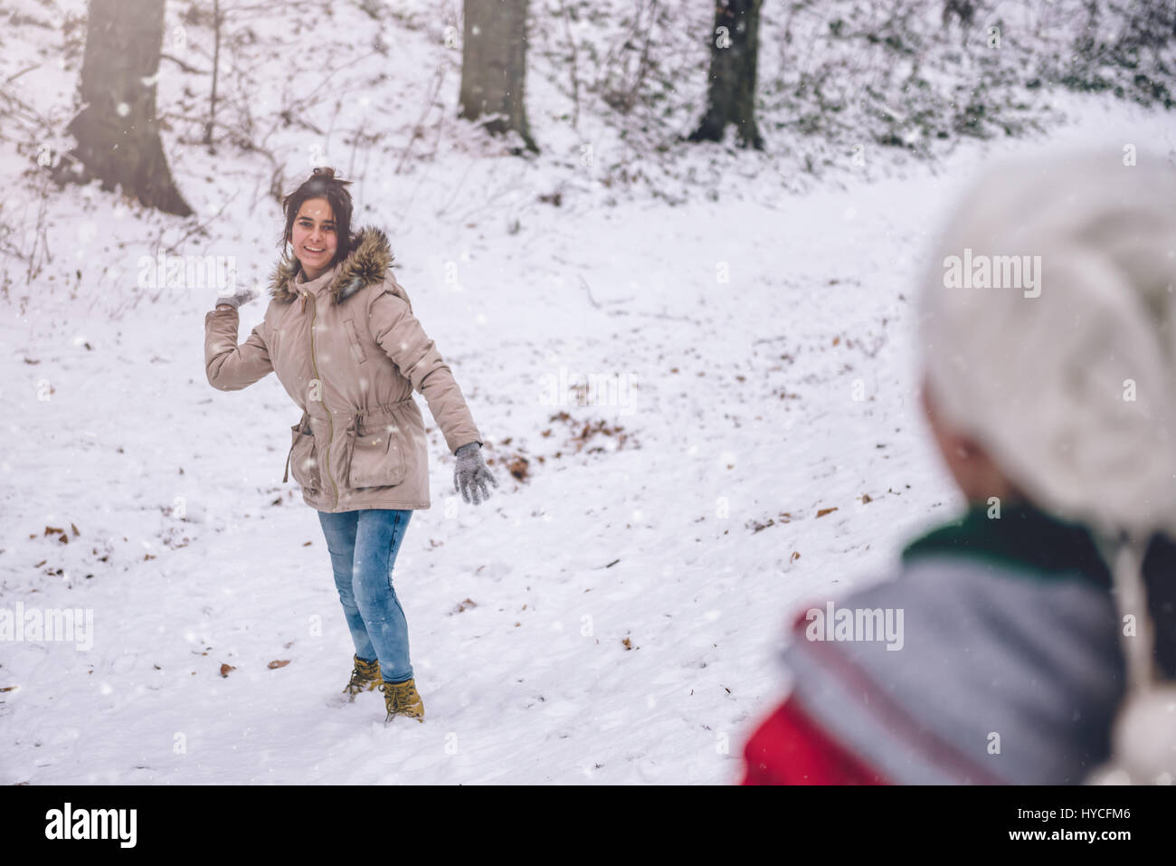 Mädchen werfen Schneeball im verschneiten Wald Stockfoto