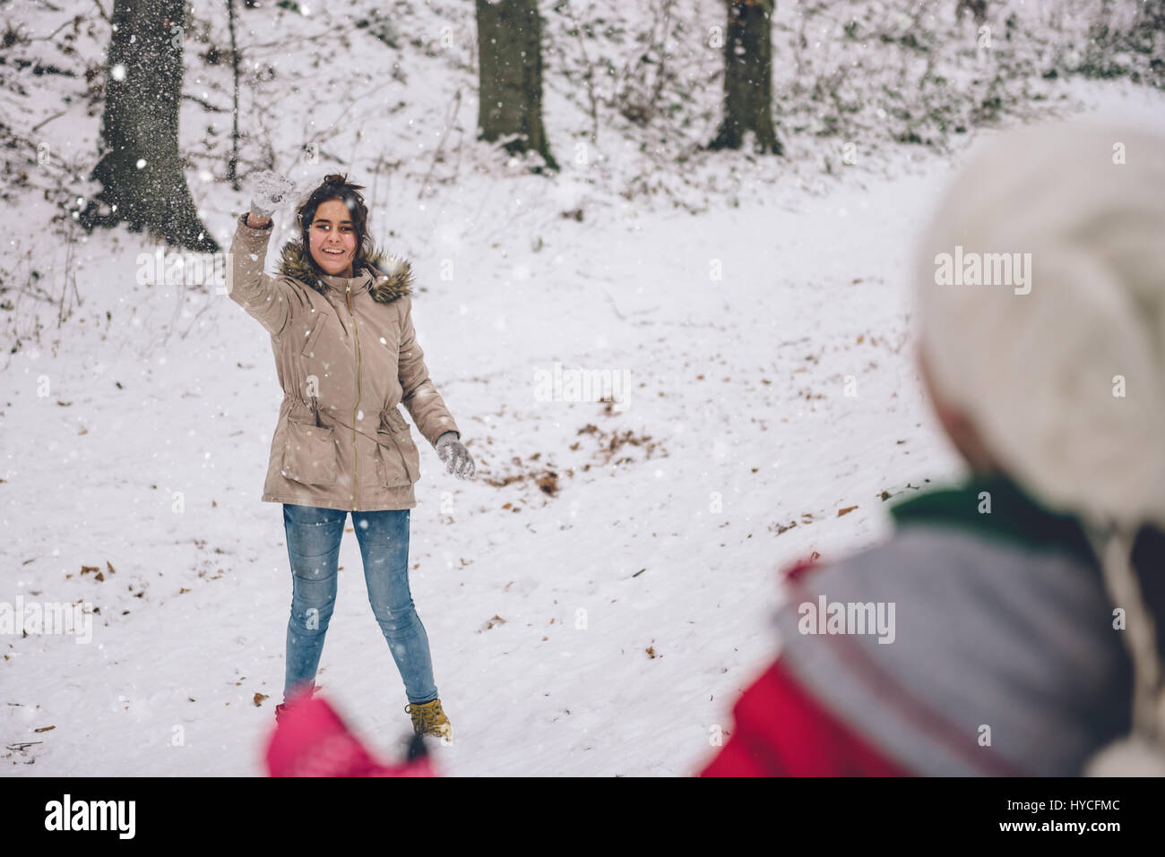 Mädchen werfen Schneeball im verschneiten Wald Stockfoto