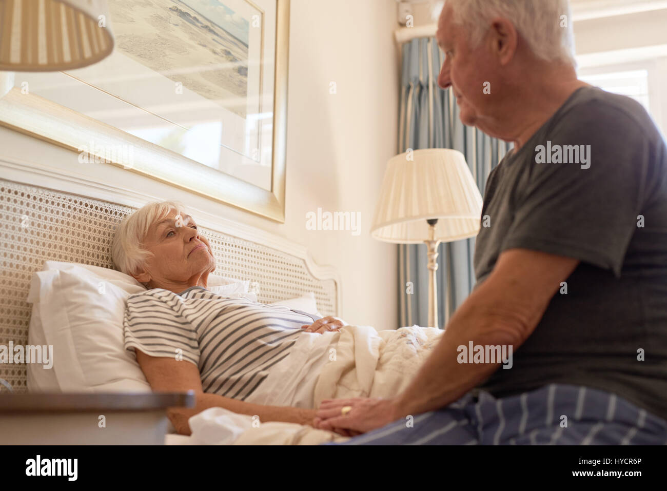 Ältere Mann kümmert sich um seine kranke Frau im Bett Stockfoto