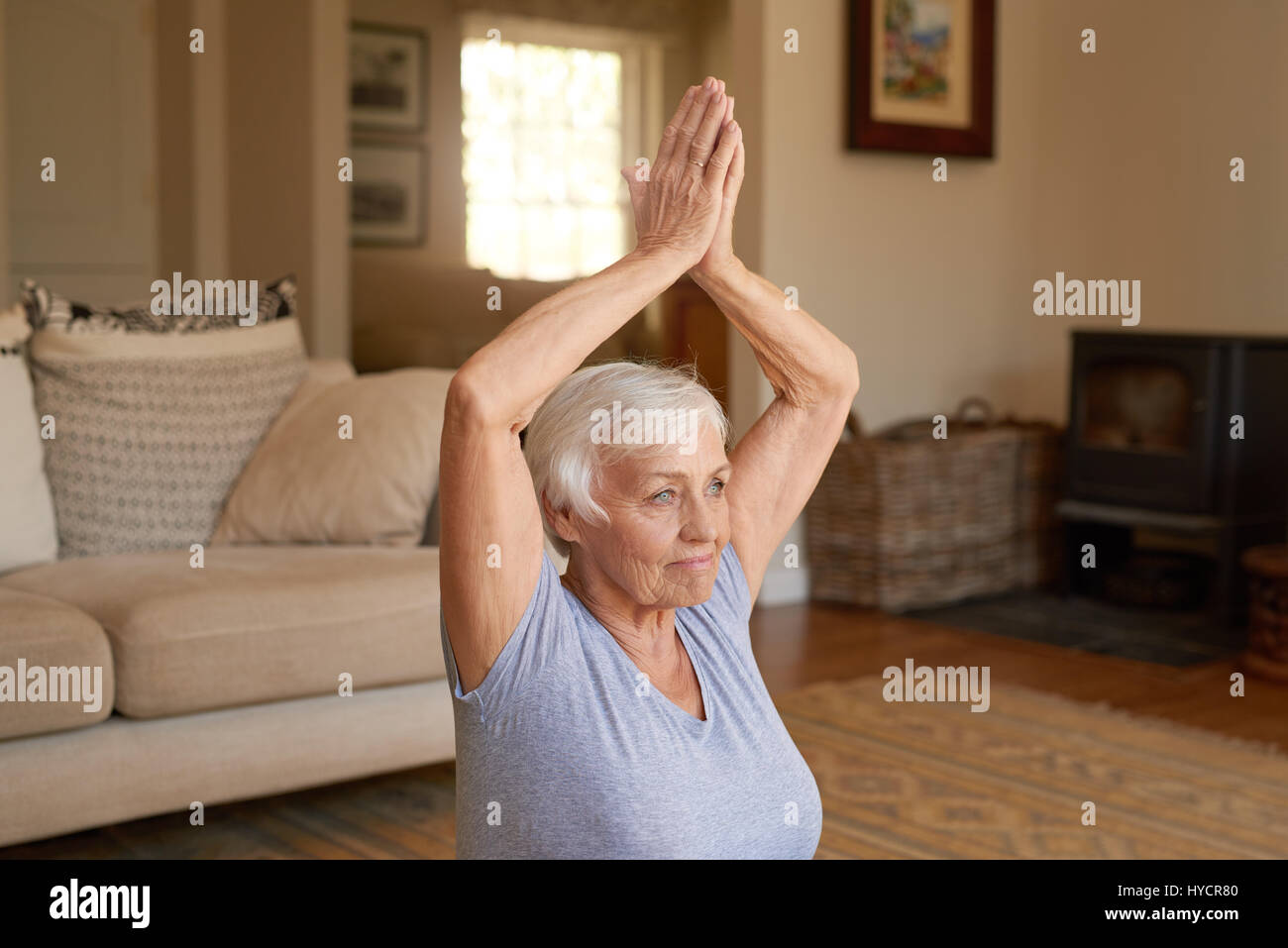 Aktive ältere Frau beim Yoga in ihrem Wohnzimmer Stockfoto