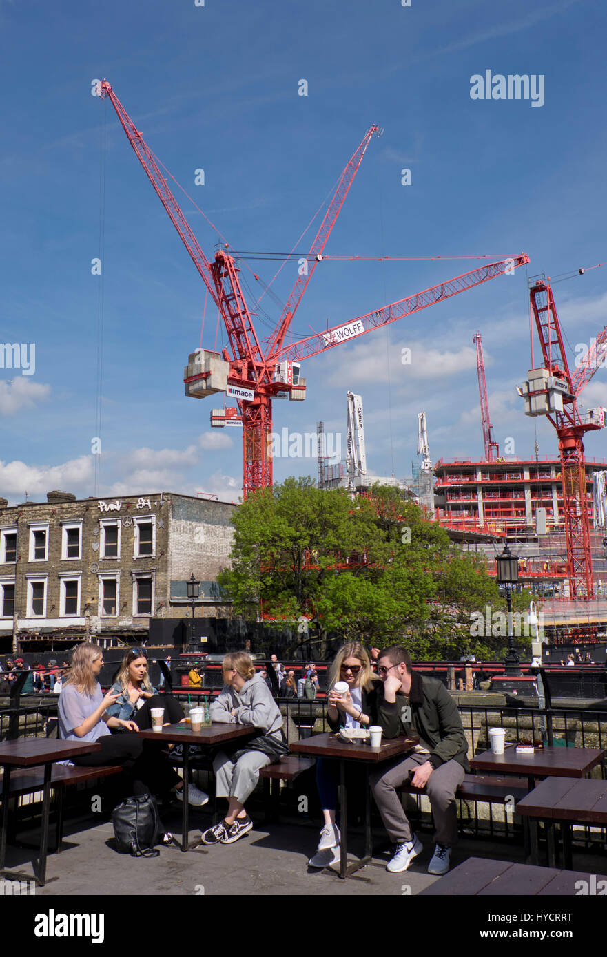 Junge Leute sitzen in einem Café von Bau und Wohnungswesen Bauarbeiten von Wohnungen und Büros von Regent es Canal für die Camden Lock Dorfentwicklung in Camden, London, England, UK Stockfoto