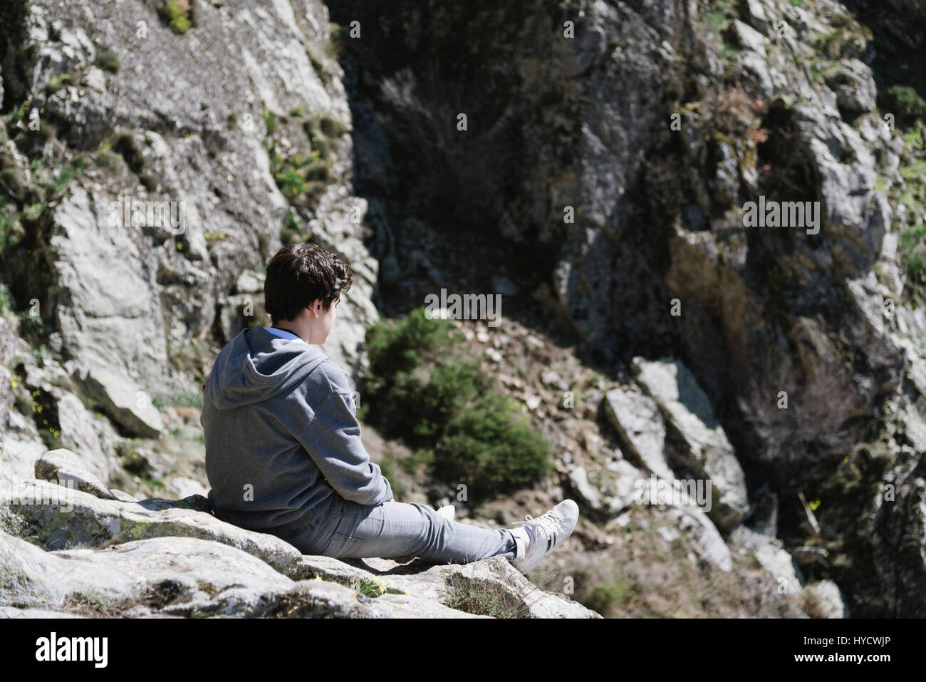 Teenager mit Freizeitkleidung sitzt auf einem Felsen Wasserfall Felsen in Madrid Gebirge blicken. Vordergrund im Fokus Stockfoto