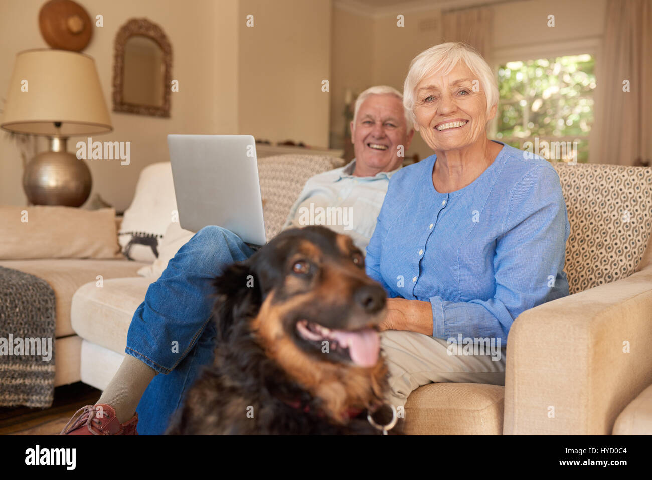 Lächelnd älteres Paar mit ihrem Hund zu Hause entspannen Stockfoto