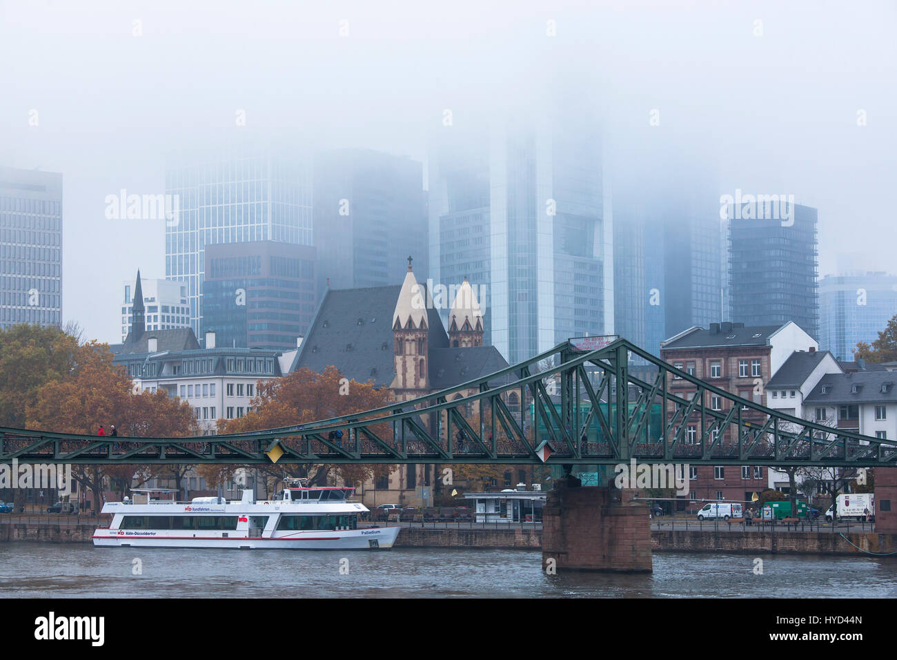 , Deutschland, Hessen, Frankfurt, Blick über den Main auf die Hochhäuser des Bankenviertels, Nebel, Eiserner Steg Brücke St. Leonhards-Kirche. Stockfoto
