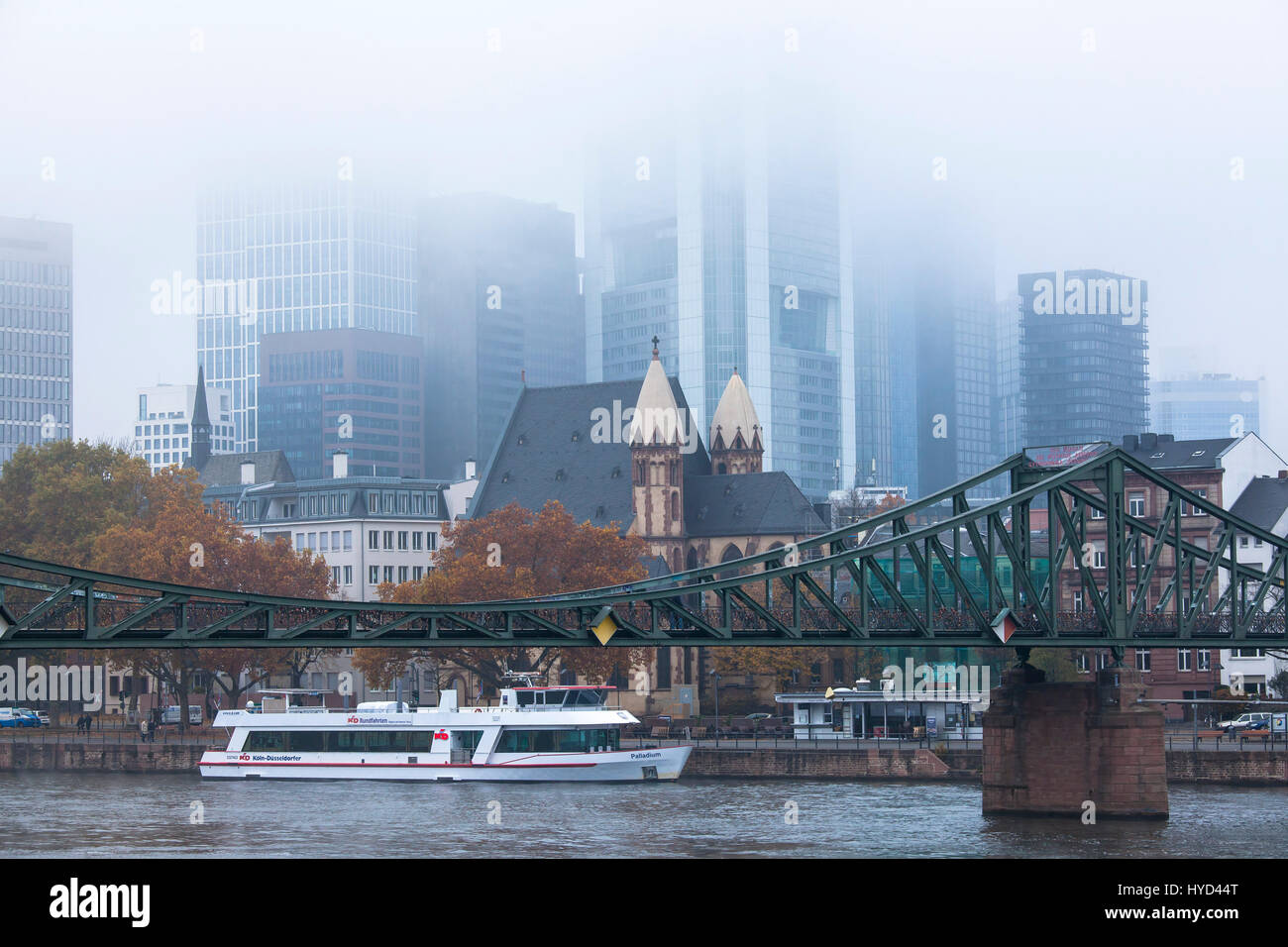 , Deutschland, Hessen, Frankfurt, Blick über den Main auf die Hochhäuser des Bankenviertels, Nebel, Eiserner Steg Brücke St. Leonhards-Kirche. Stockfoto
