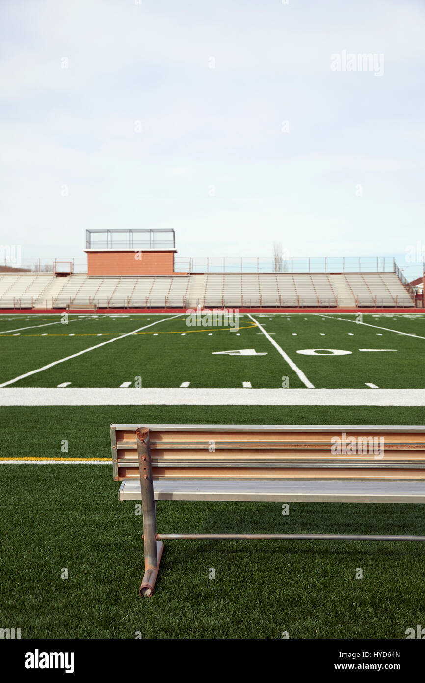 American Football Field mit Bank im Vordergrund und leere Tribüne Im Hintergrund Stockfoto