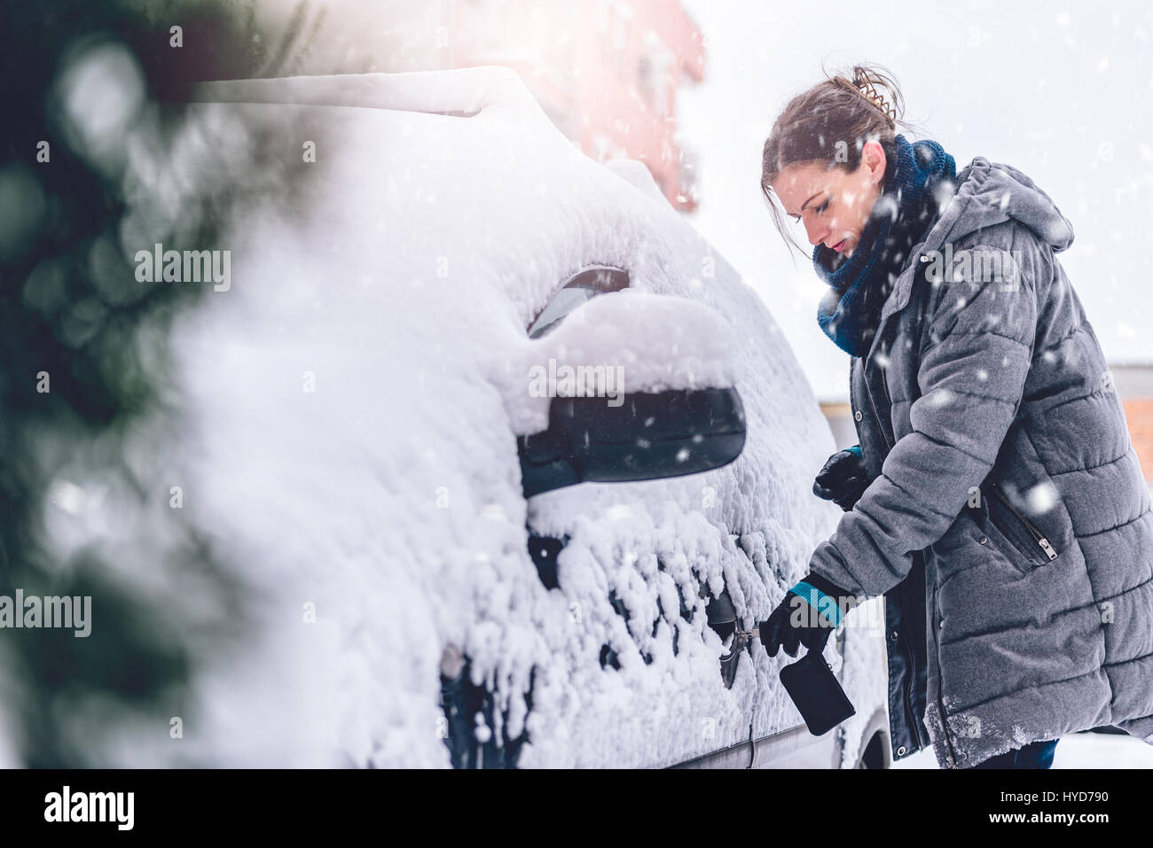 Frau trägt grauen Winter Jacke und Leder Hand entriegeln Schnee bedeckten Auto Handschuhe Stockfoto
