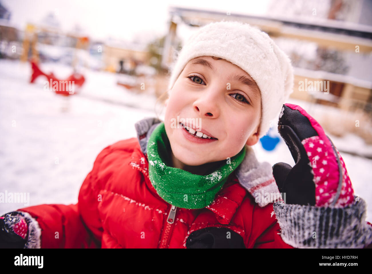 Kleine Mädchen tragen rote Jacke und weißem Hut spielen im Schnee Stockfoto