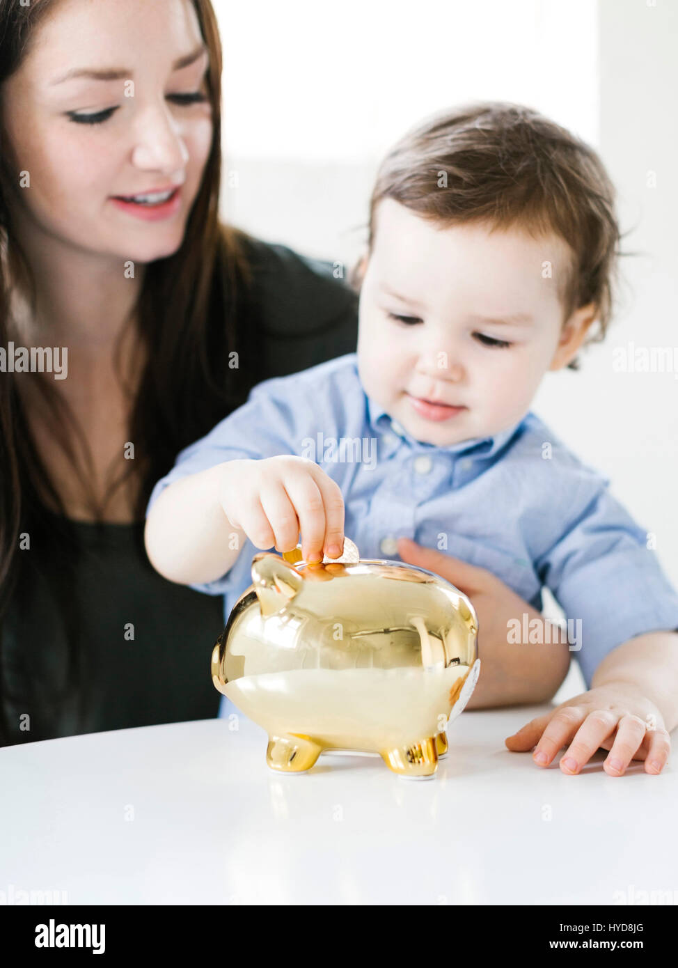 Mutter lehrt Sohn (4-5), wie man Geld spart Stockfoto